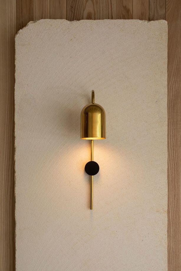 A sleek golden sconce illuminates the natural beauty of the limestone.