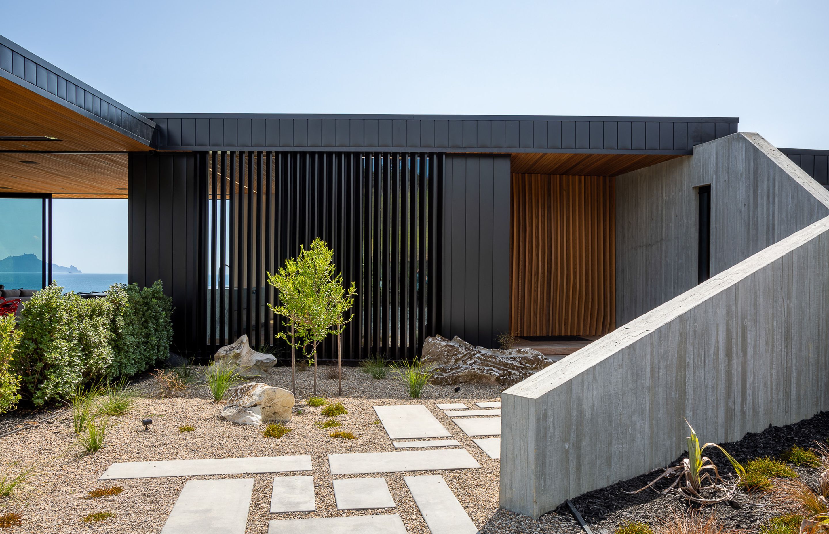 The in situ concrete wall and cedar and aluminium fins that define the entry set the angular theme that is seen in the rest of the house, particularly in the striking gabled ends of the two wings.