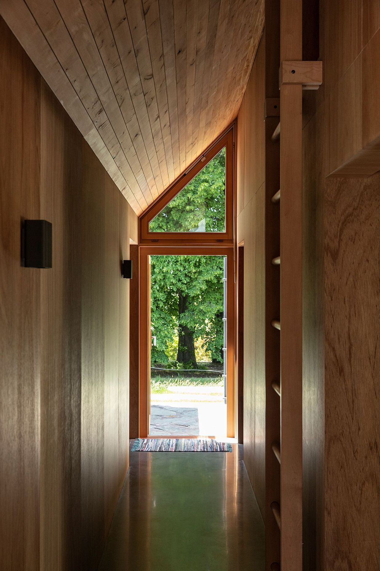 The corridor lines up with a large oak tree, accentuated by the steeply angled roof.