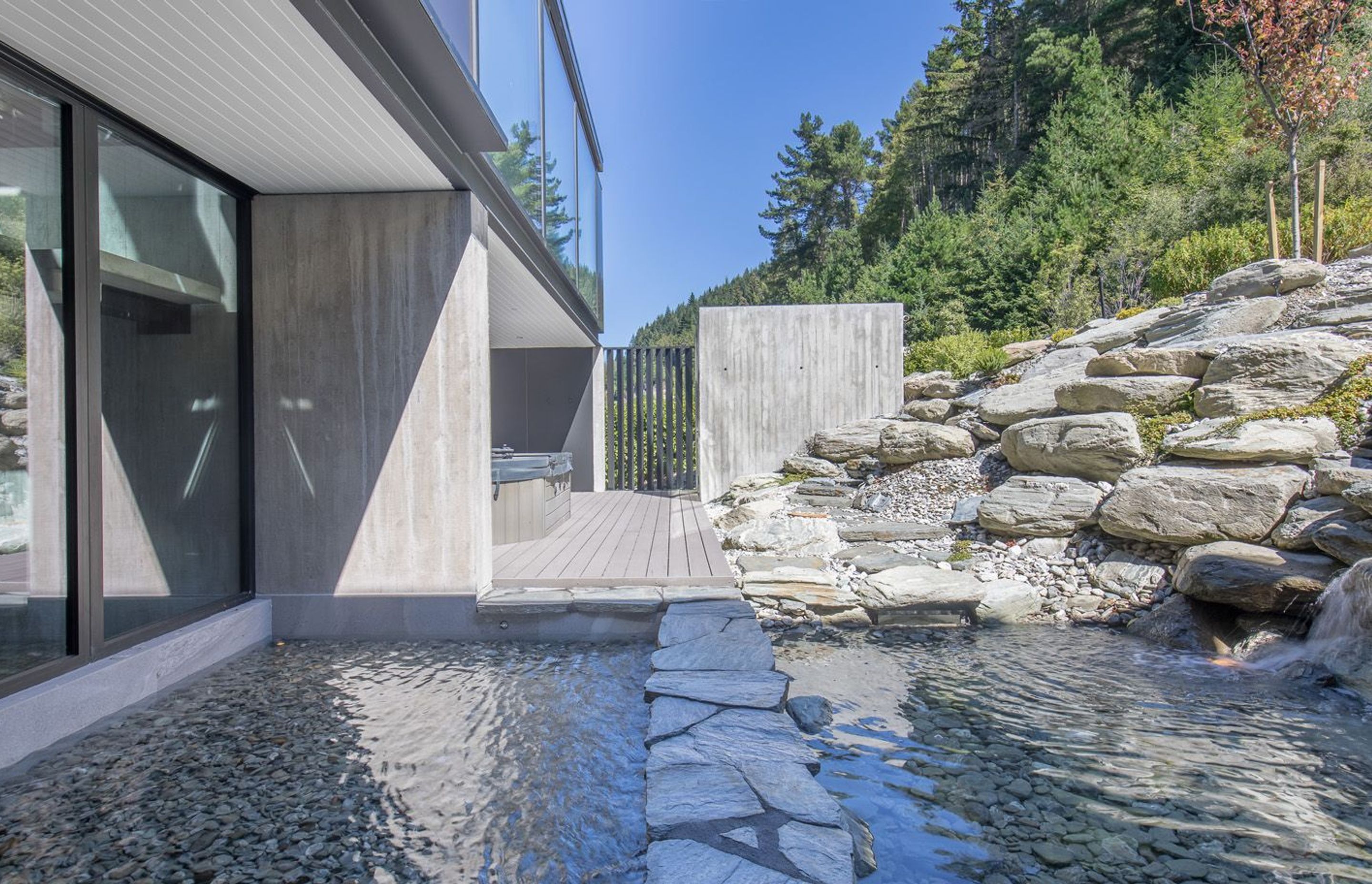 The waterfall trickles in a reflection pond which has a stone path across the middle, which leads to the spa pool and sauna accessed from the hallway to the family bedrooms.