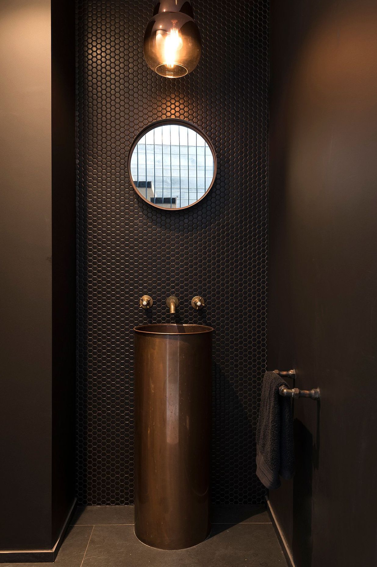 Tiling, tapware and pedestal basin in copper create a warm and elegant bathroom.
