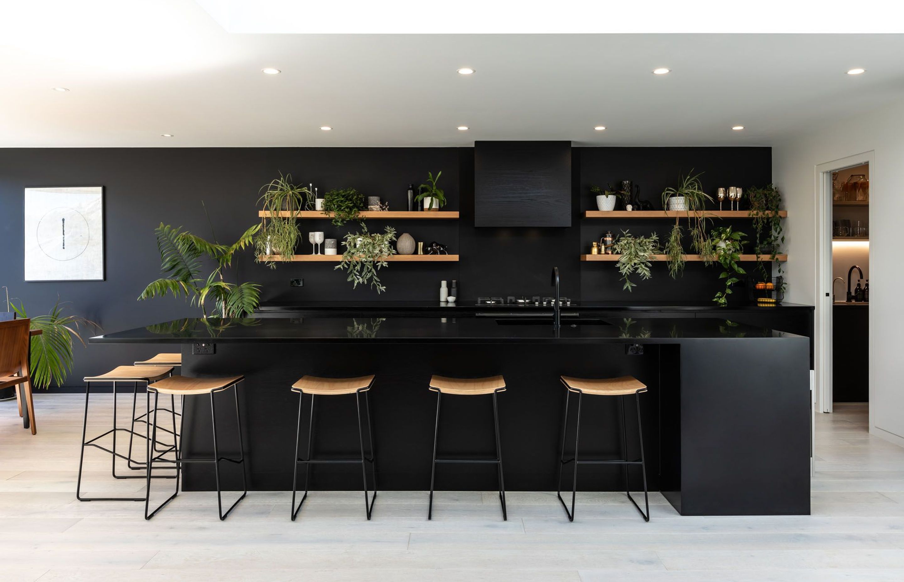 The kitchen has been designed to recede into the background through a clever use of colour and indoor plants.