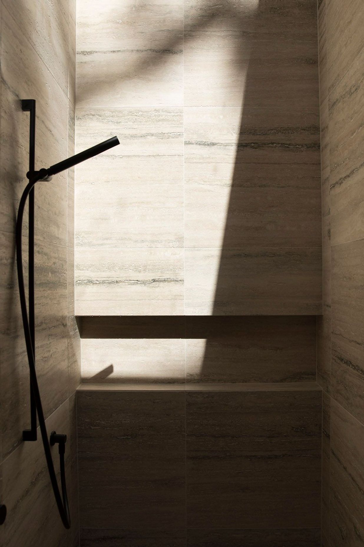 This travertine-lined shower is lit from above via a skylight.