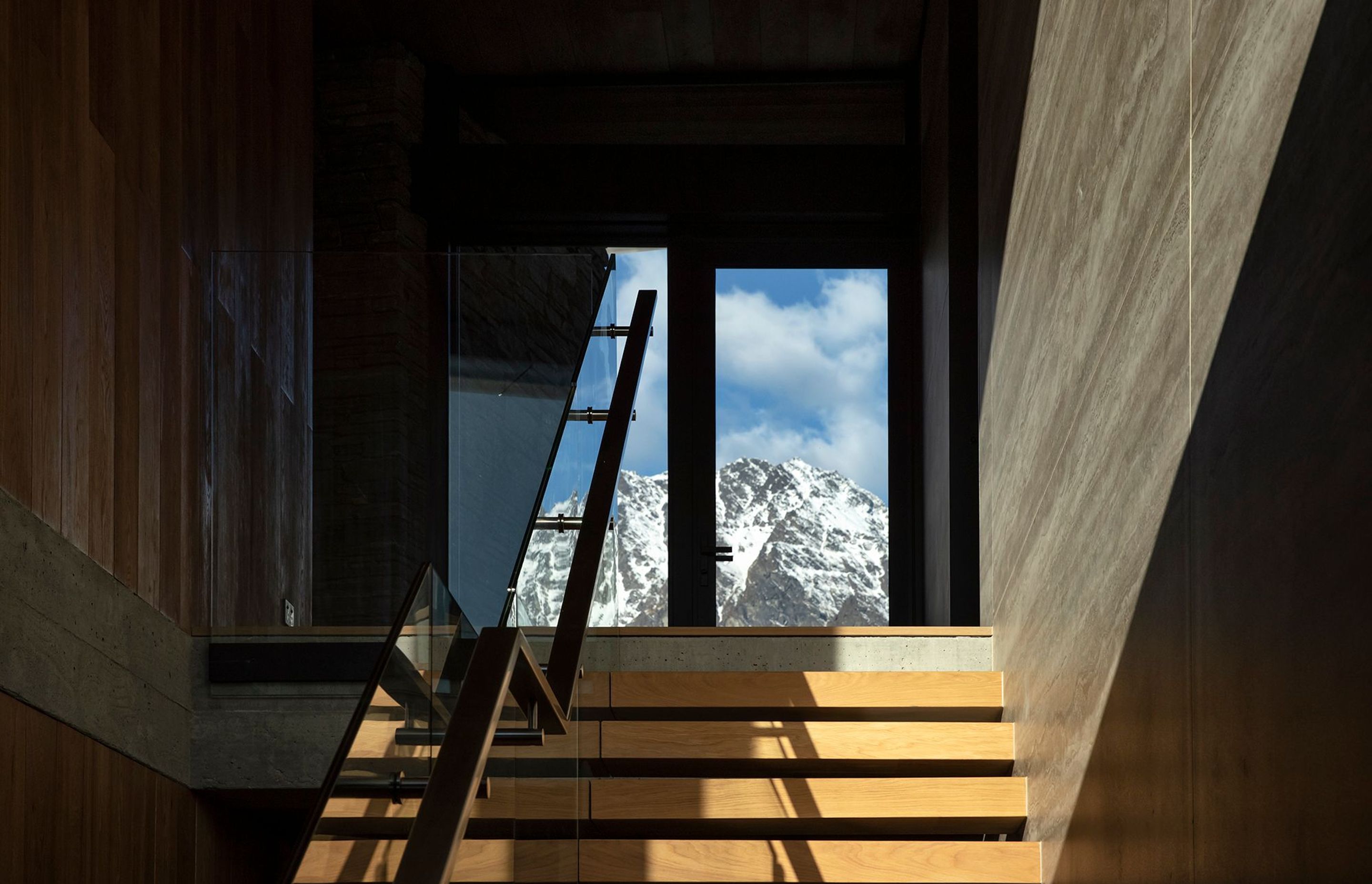 Floor-to-ceiling glazing at the top of the stairs reveals a view of The Remarkables, The staircase features matt-finished travertine panelling. Photograph: Simon Devitt.