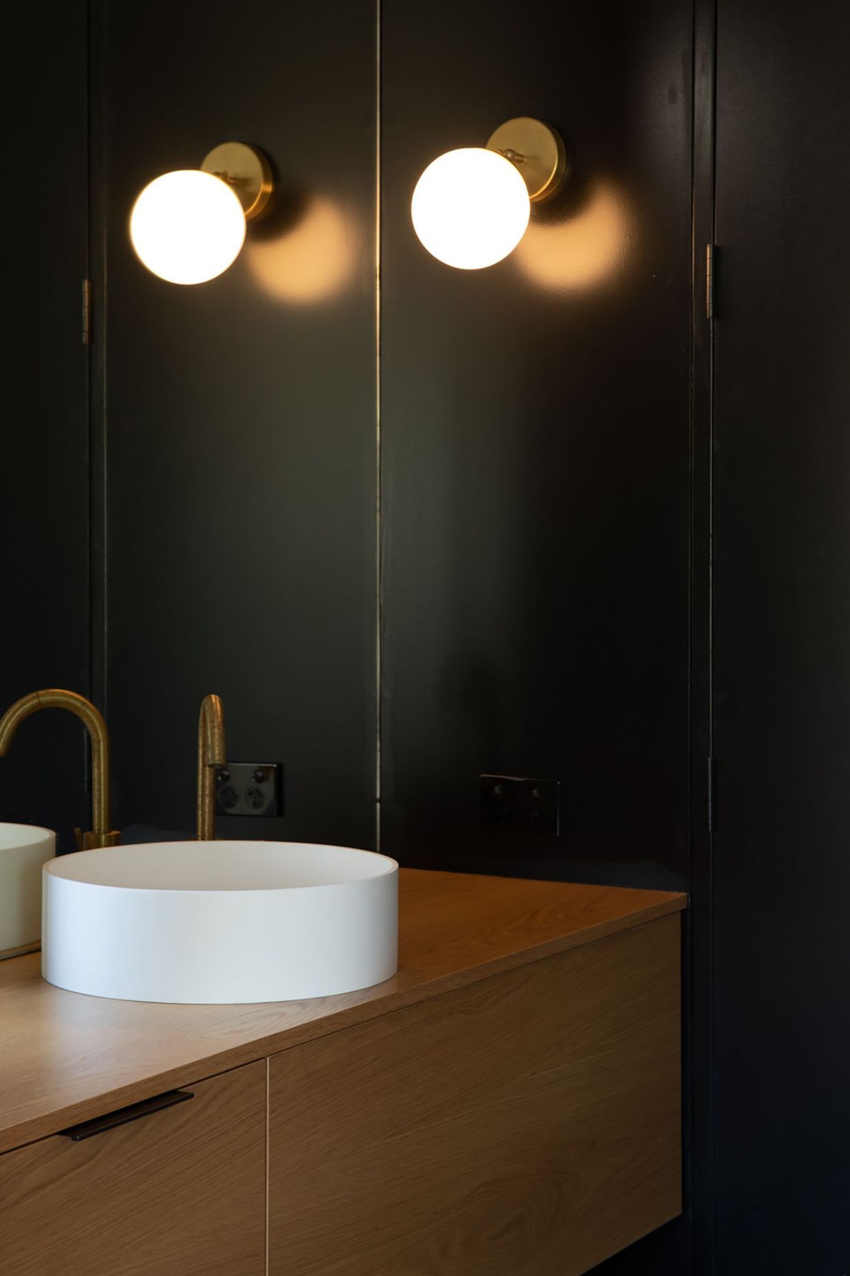 A moody bathroom utilises natural materials and feature lighting.