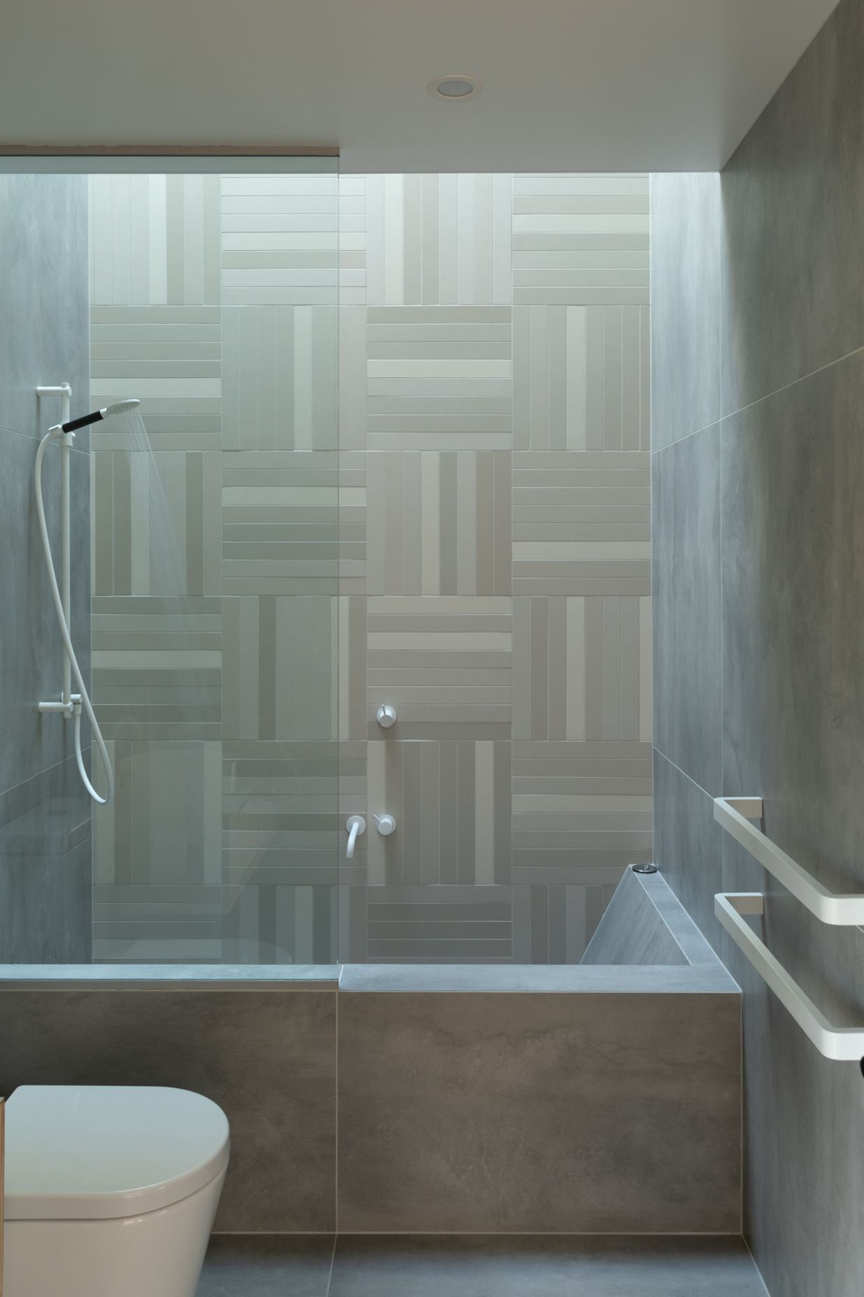 Rectangular mosaic tiles and white tapware create an elegant bathroom.