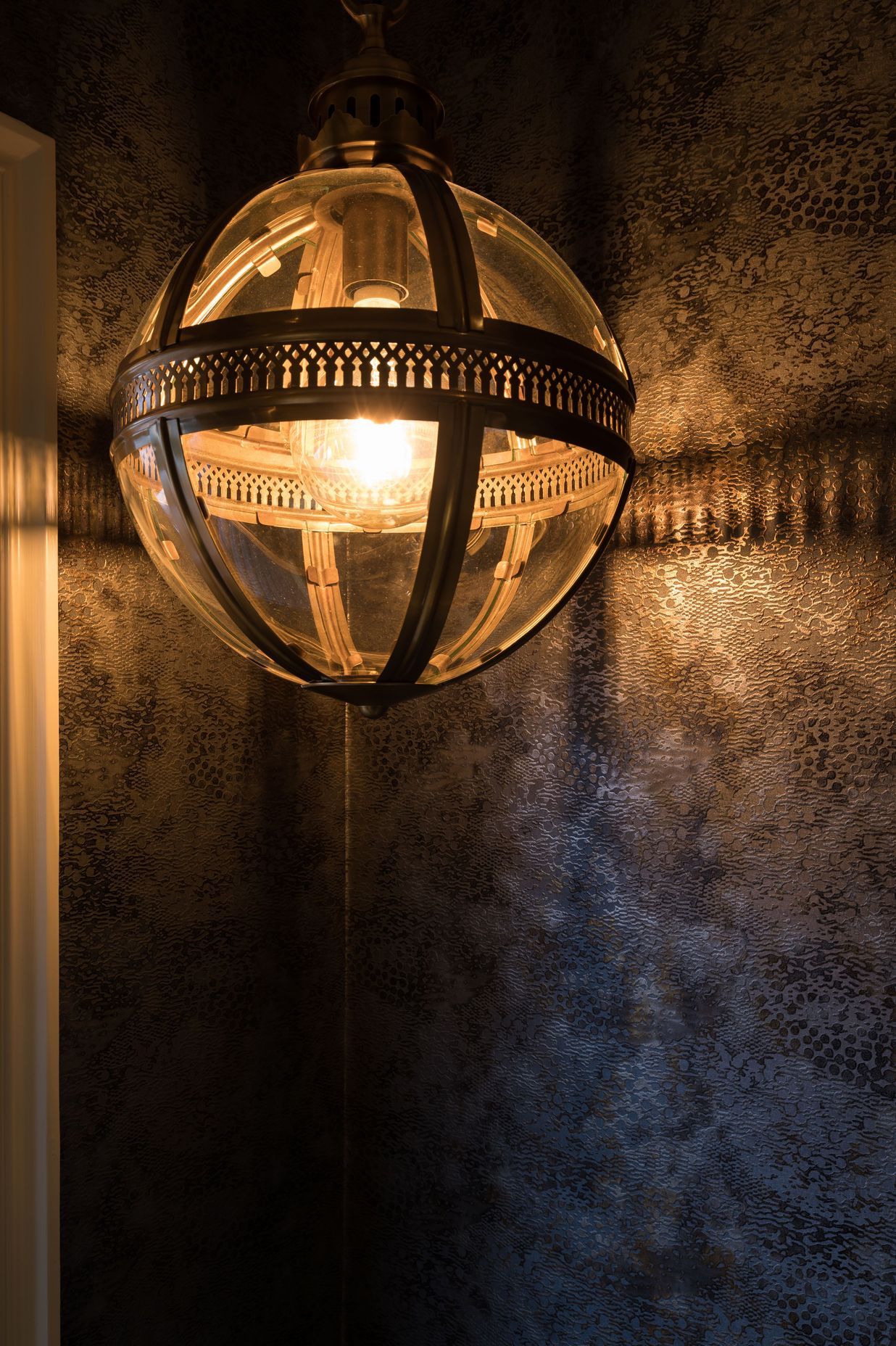 Combined Laundry and Powder Room - Cassamance textured gold and balck wallpaper, highlighted by the gold pendant light
