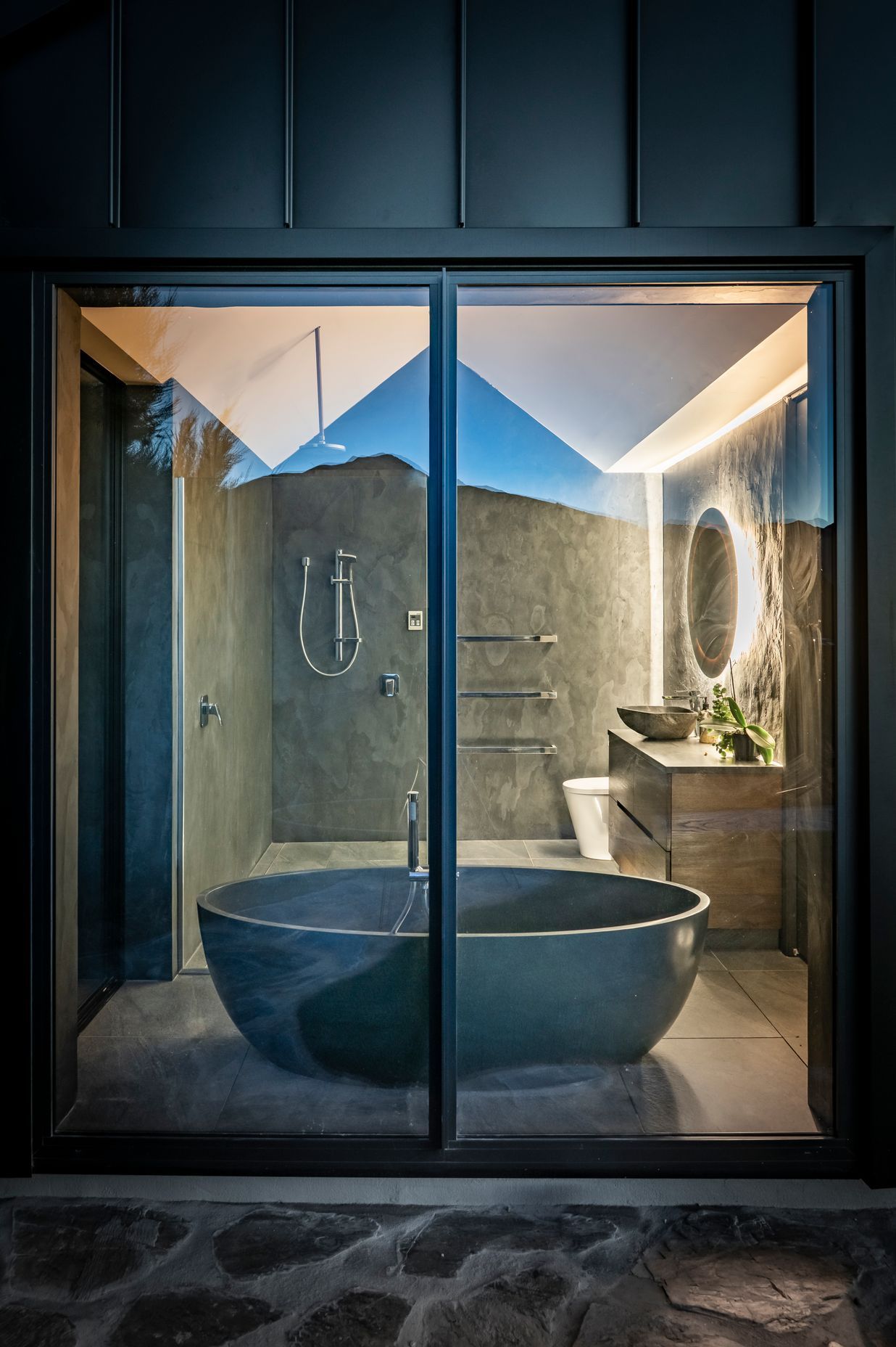 An exterior view of the bathroom with its striking black stone oval-shaped bath.