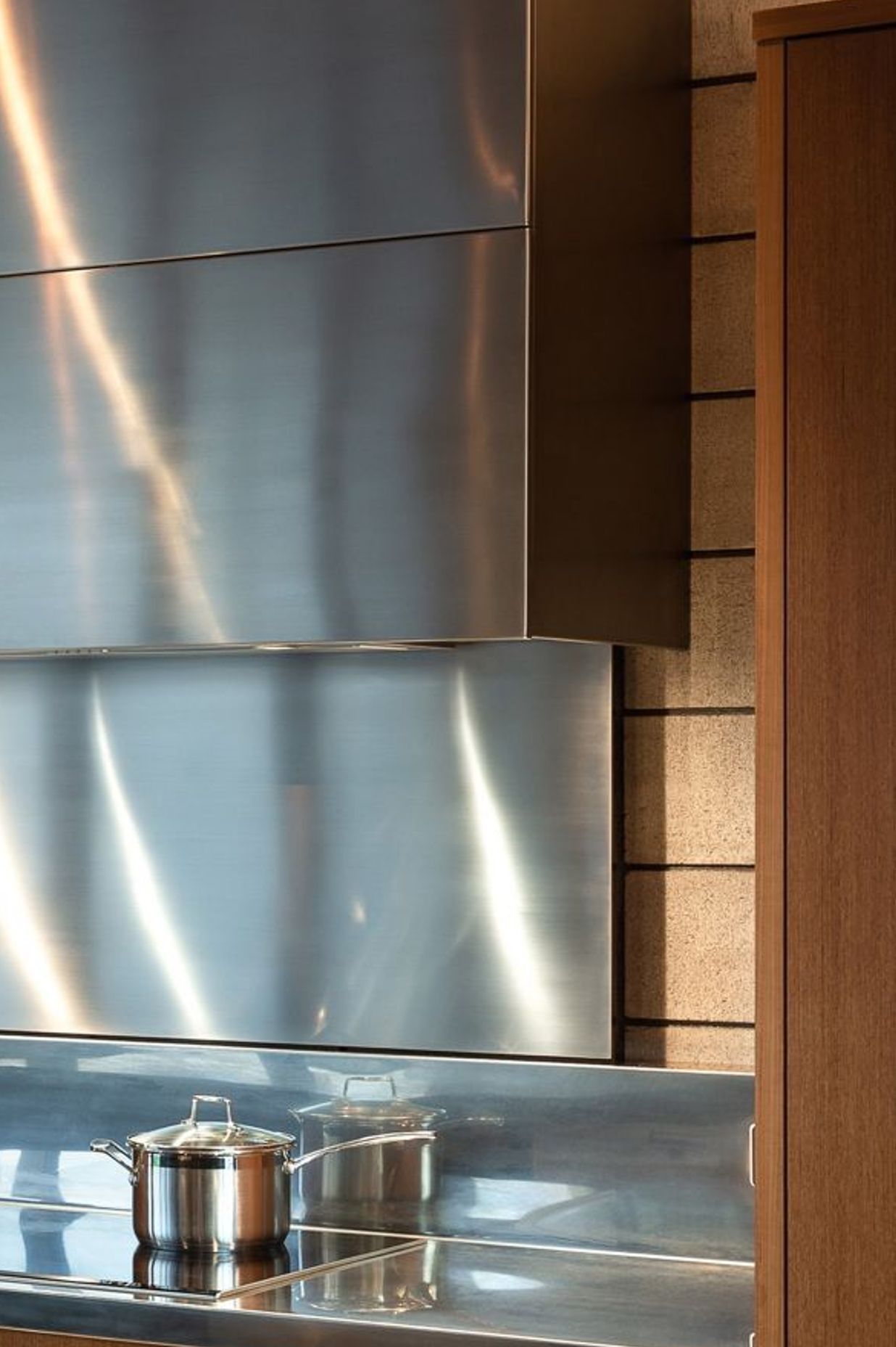 A custom stainless-steel ventilation cabinet is likewise separated from the warm teak to celebrate the block’s raw beauty. To protect the concrete surface long-term, I conceived a retractable 6mm-thin steel sheet splashback. 