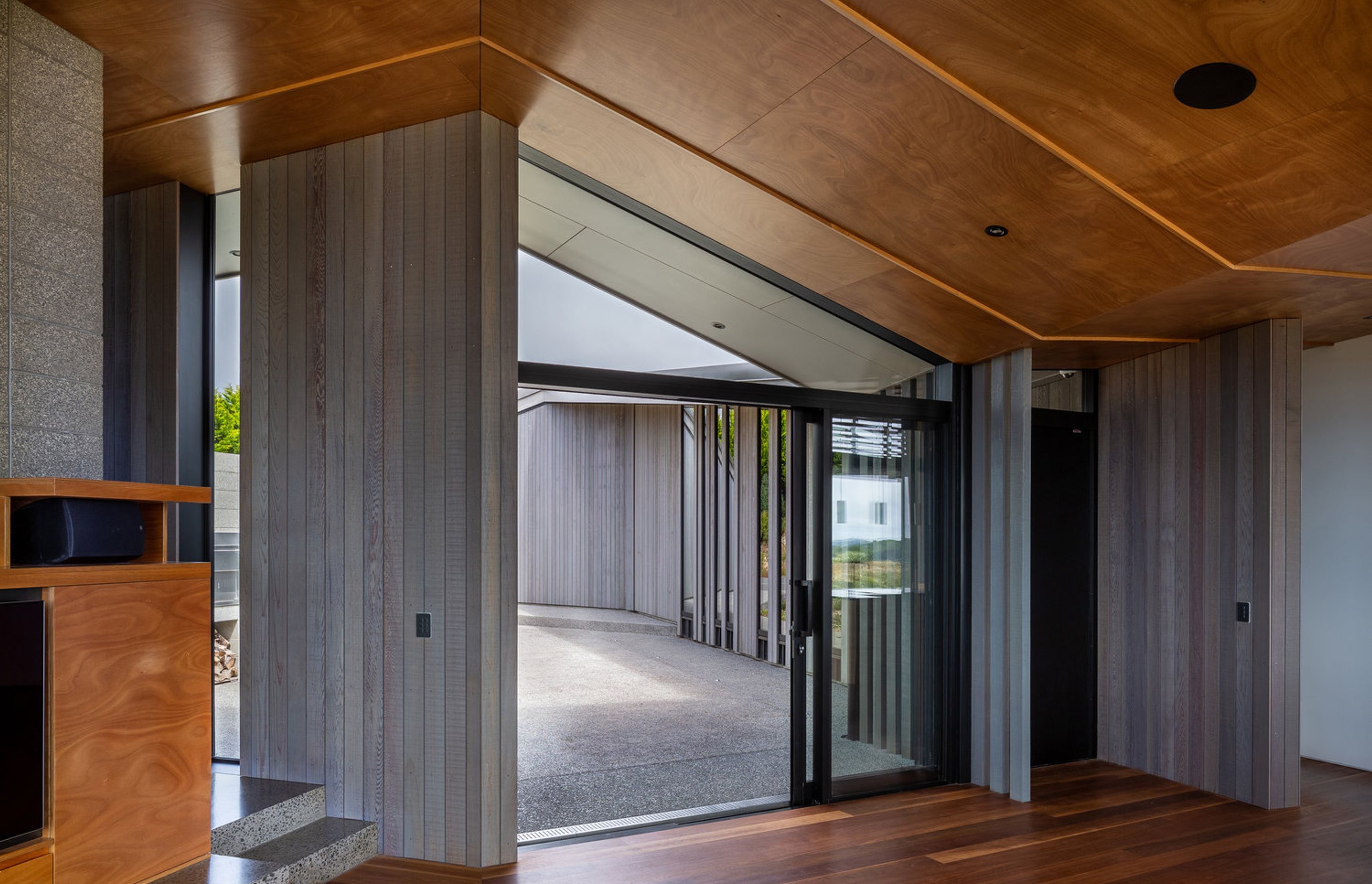 Oiled cedar cladding and concrete continues into the hallway, merging inside and outside.
