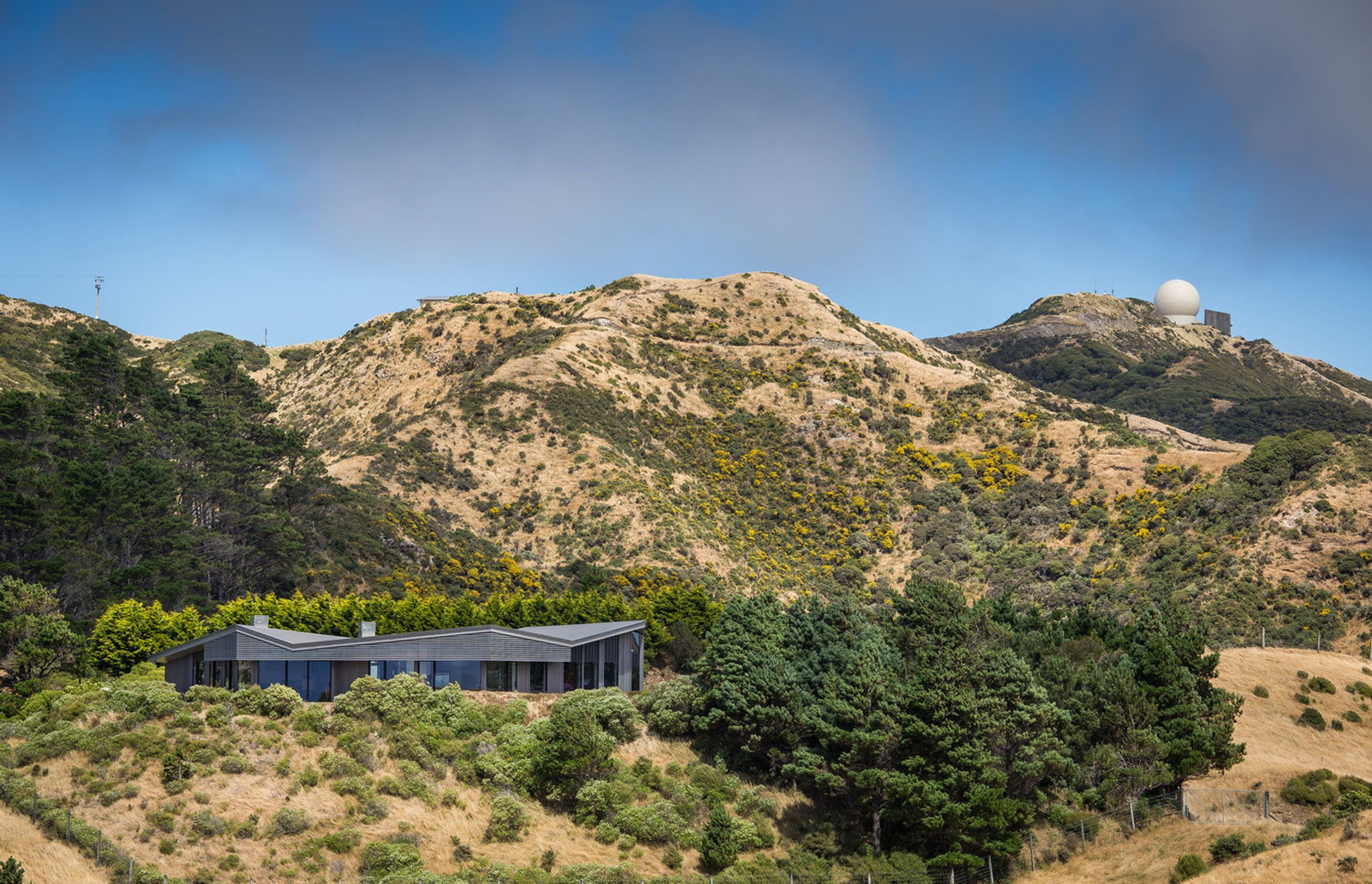 This contemporary rural house tops off a hill excavated a long time ago, completing its form. Its low-slung form is "slightly undulating – like the rolls of the neighbouring hills."