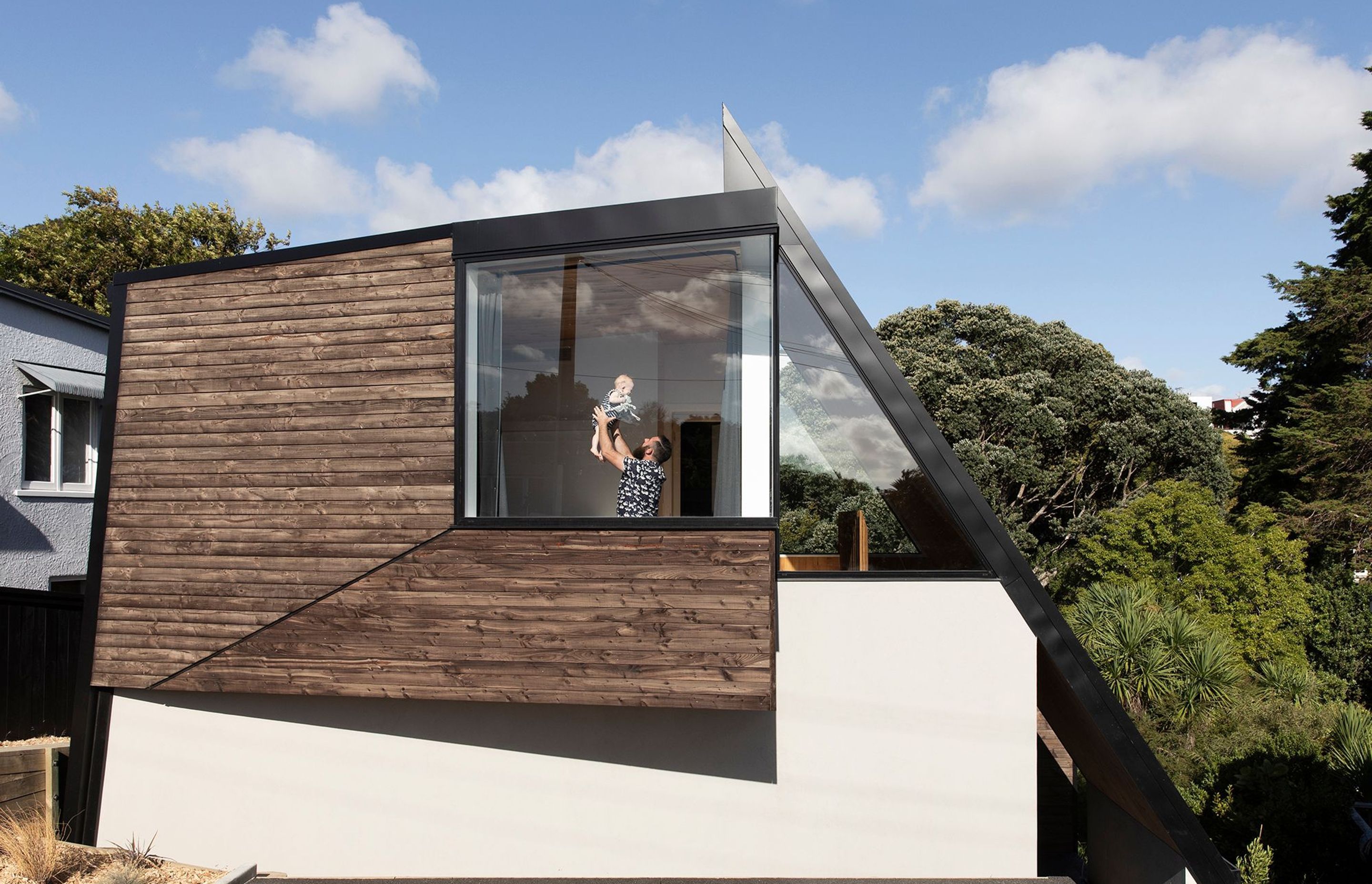 Designer Craig Wilson with his son in the master bedroom. The faceted timber cladding is treated with iron vitriol by Abodo.