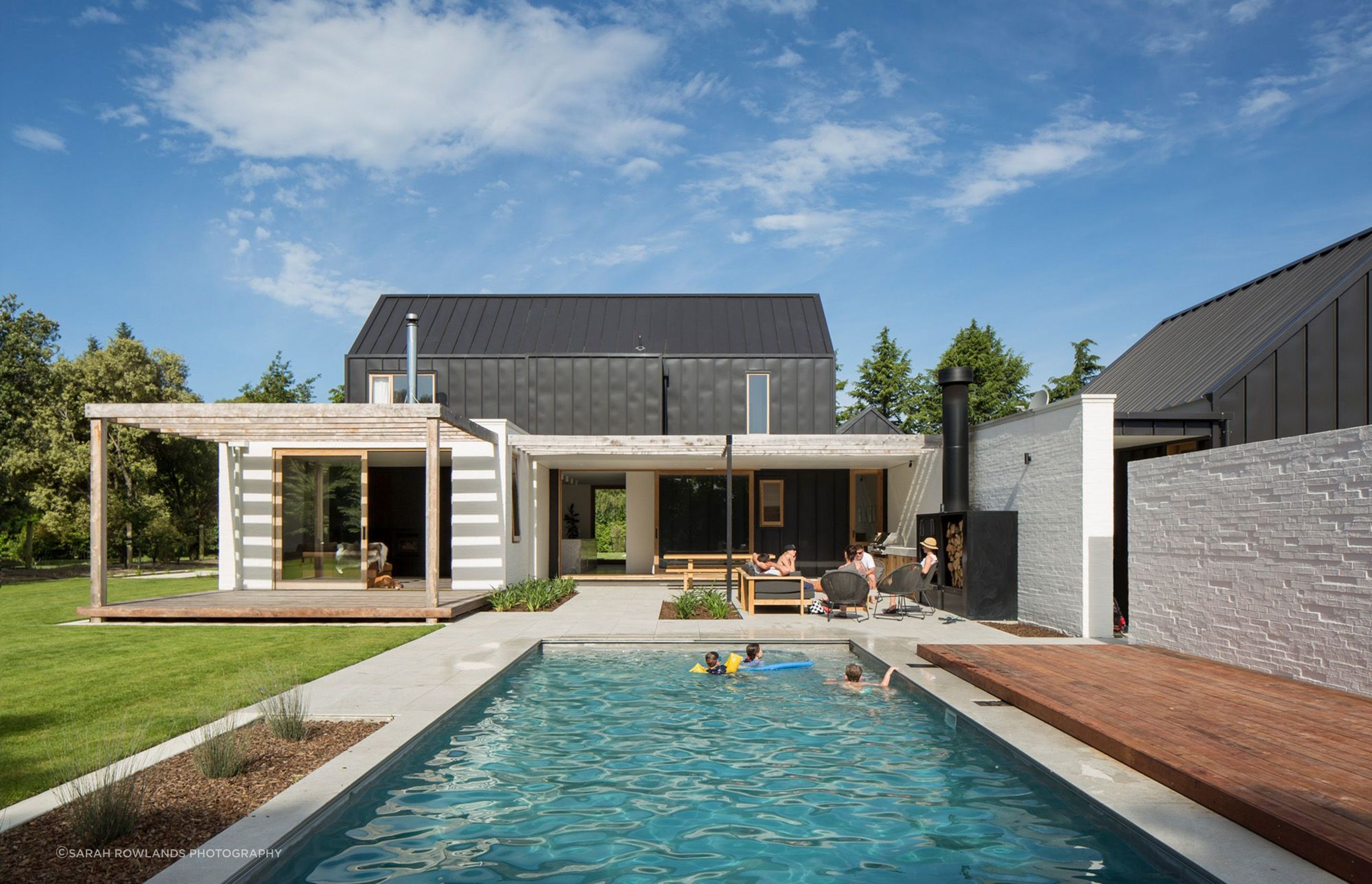 A swimming pool and outdoor entertaining areas are sheltered by a white bagged-brick wall painted in Dulux 'Dannevirke' to match the rest of the house.