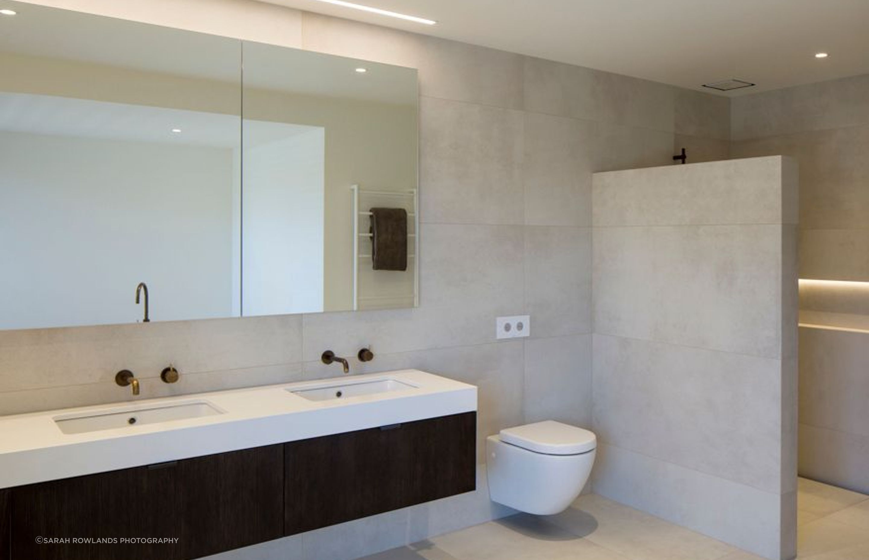 The ensuite bathroom features a custom-built cabinet with dark oak veneer and a stone top. 