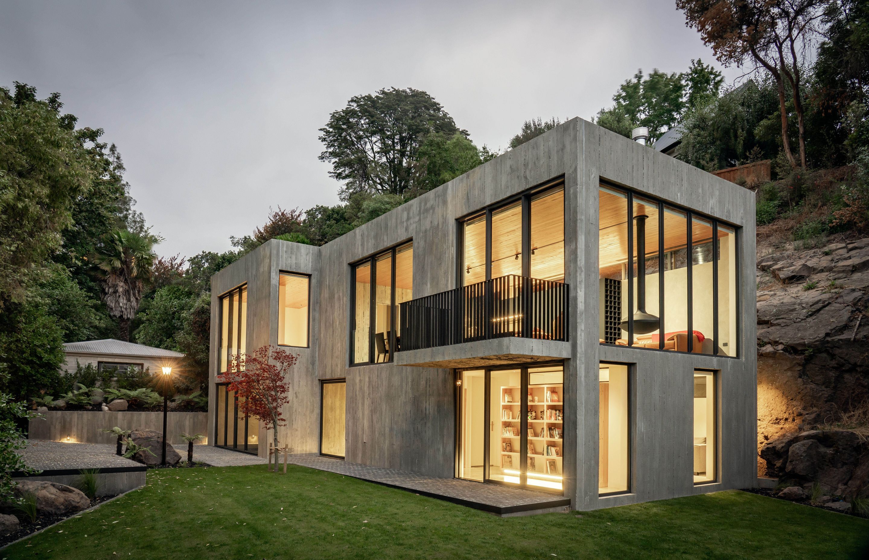 The Brutalist concrete form is punctured by full height glazing on both levels of this two-storyed home.