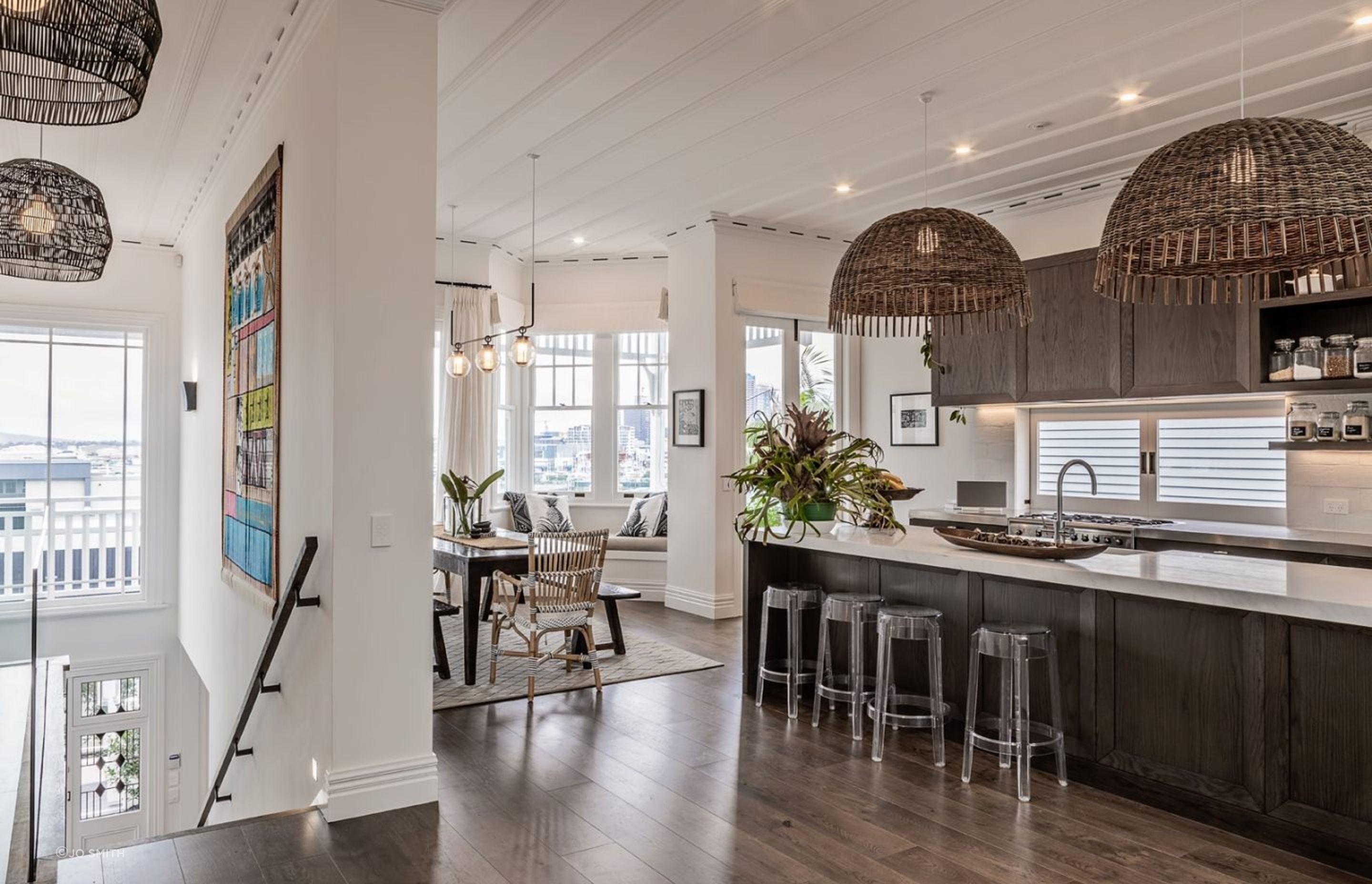 The open-plan kitchen and dining room leads to a bay window overlooking the city. An original board-and-batten ceiling, painted white to match the walls, provides a contrast to the dark oak flooring and cabinetry.