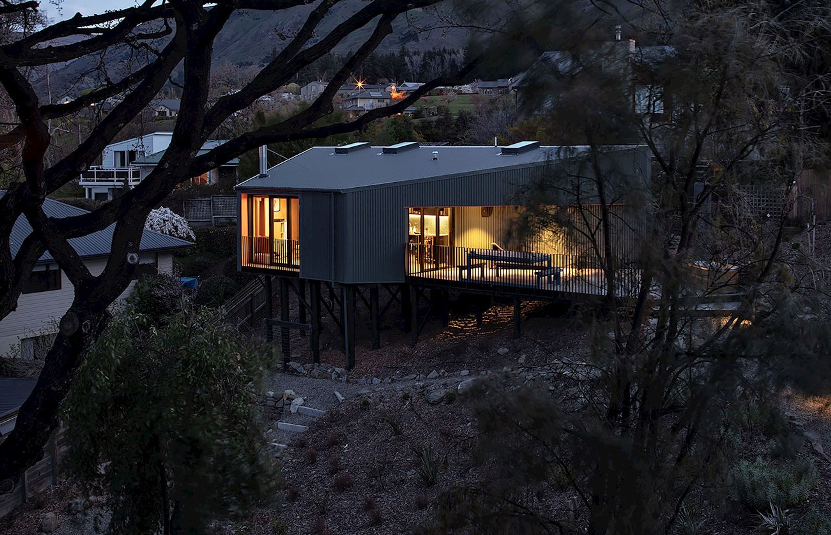 On a very steep site in Wanaka, this modest holiday home is elevated up on poles, like a kea bird perched in the trees.