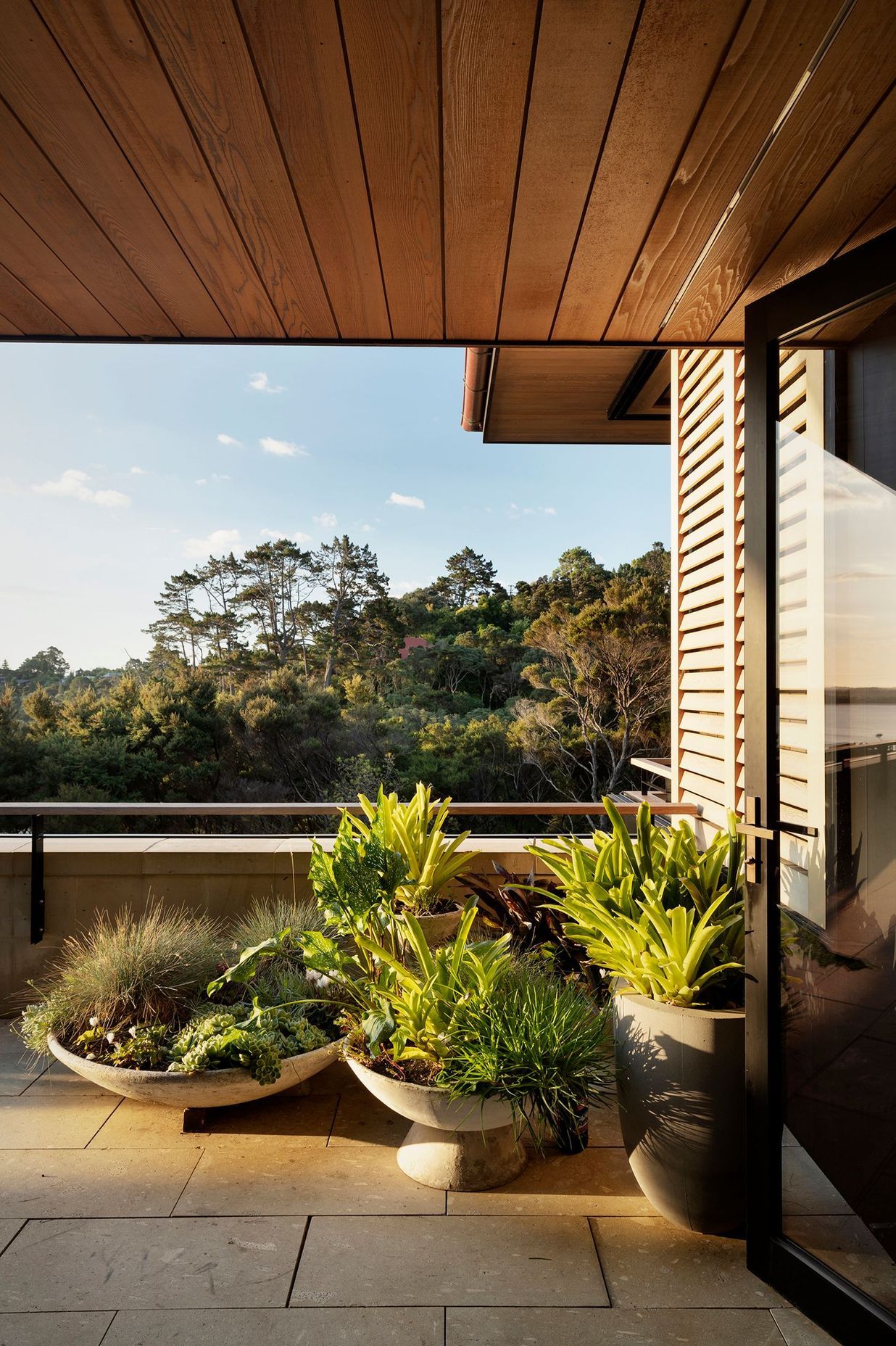 Potted plants blend the terrace in with the view of rejuvenating bush.