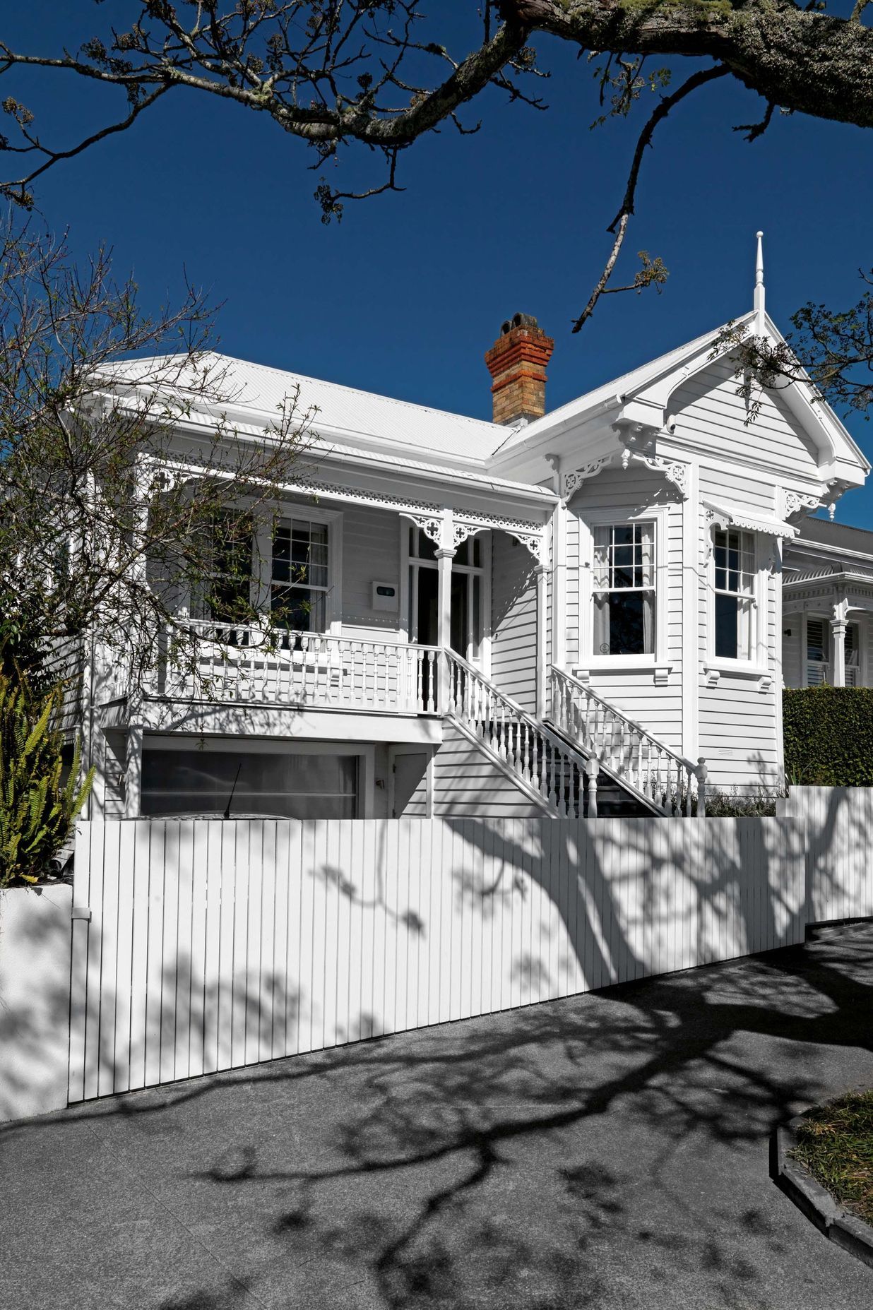 The front elevation is a classic Ponsonby villa with a bay window and verandah – looking fresh and crisp painted all in white.