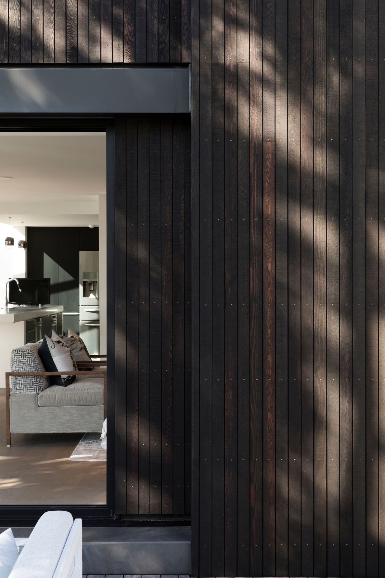 Narrow boards of black-stained cedar cladding create a pinstriped effect.