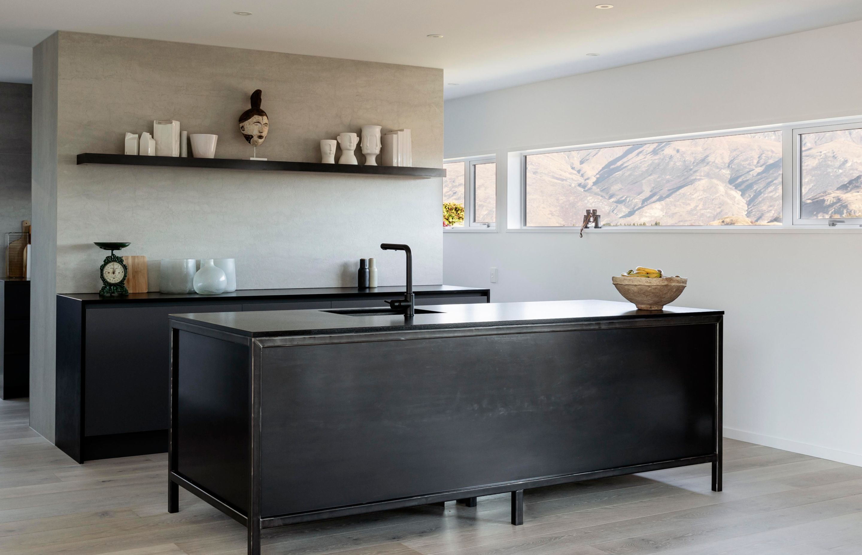 The bold, dark kitchen features cabinetry that looks like furniture placed into the space.