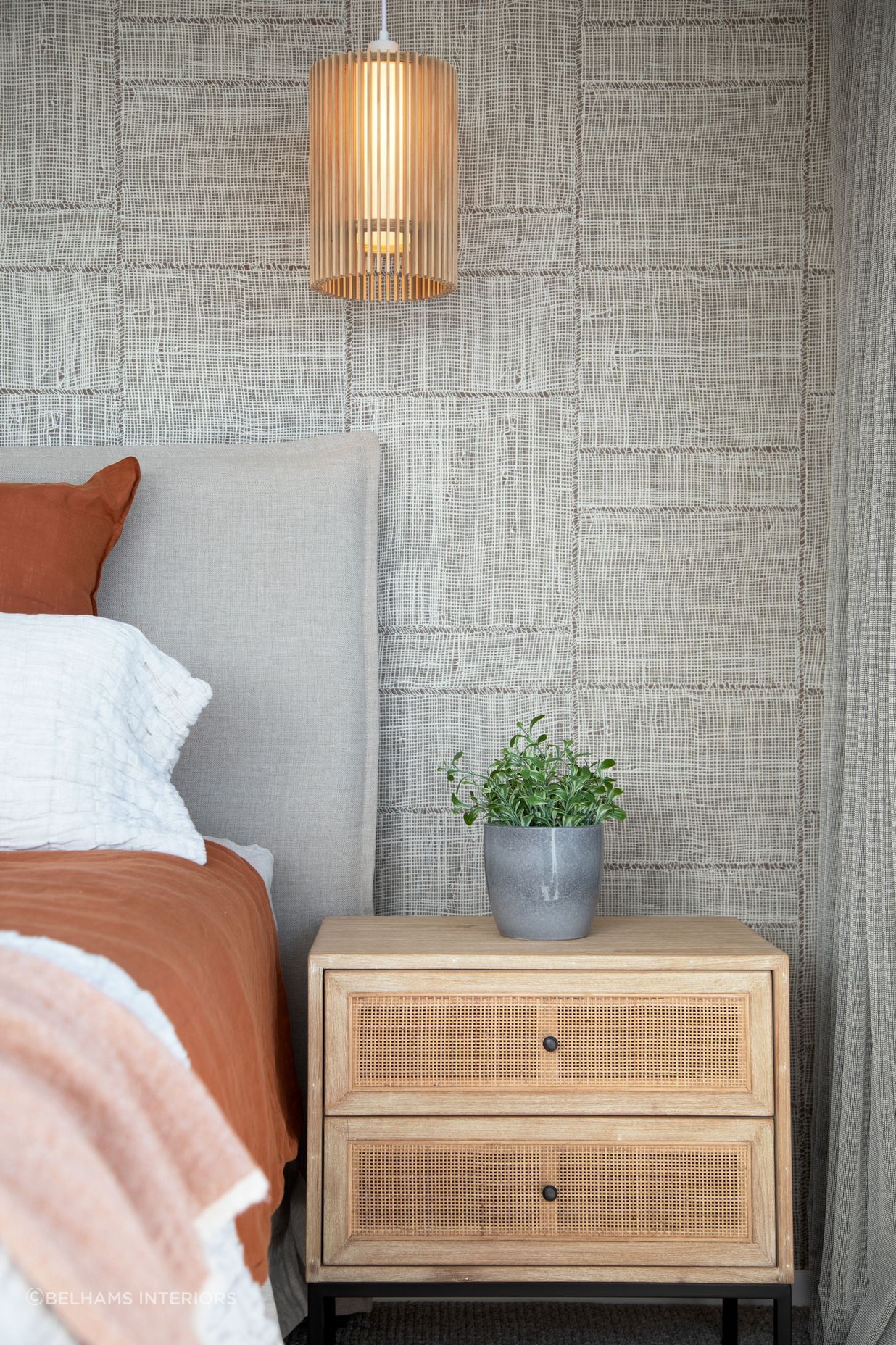 Rust bedroom with feature wallpaper, lighting and rattan bedside tables. Photographer - Sandra Henderson