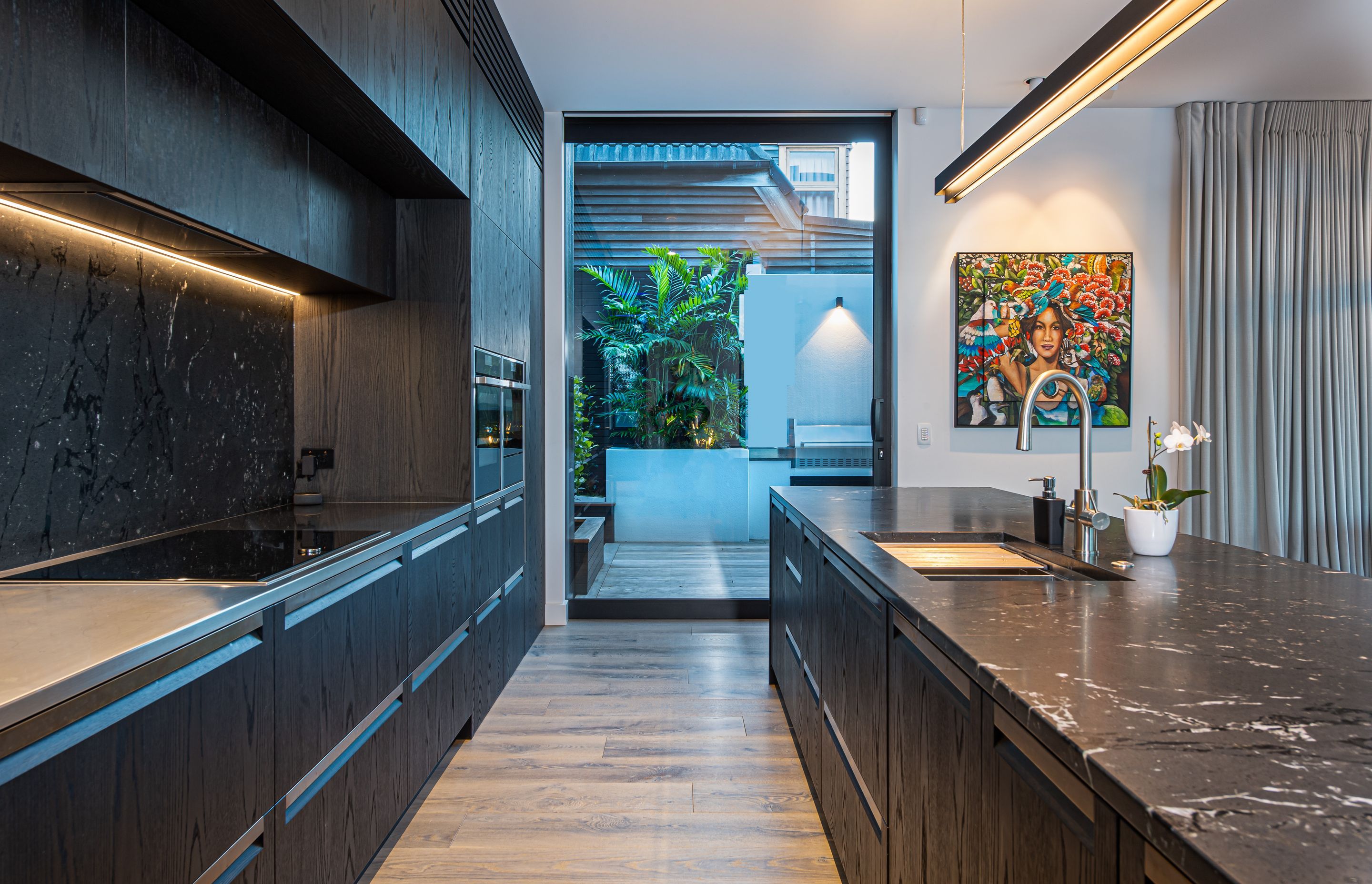 A deeply patterned stone was chosen for the island benchtop and the splash back, along with darkly stained timber cabinetry to continue the visual aesthetic established externally.