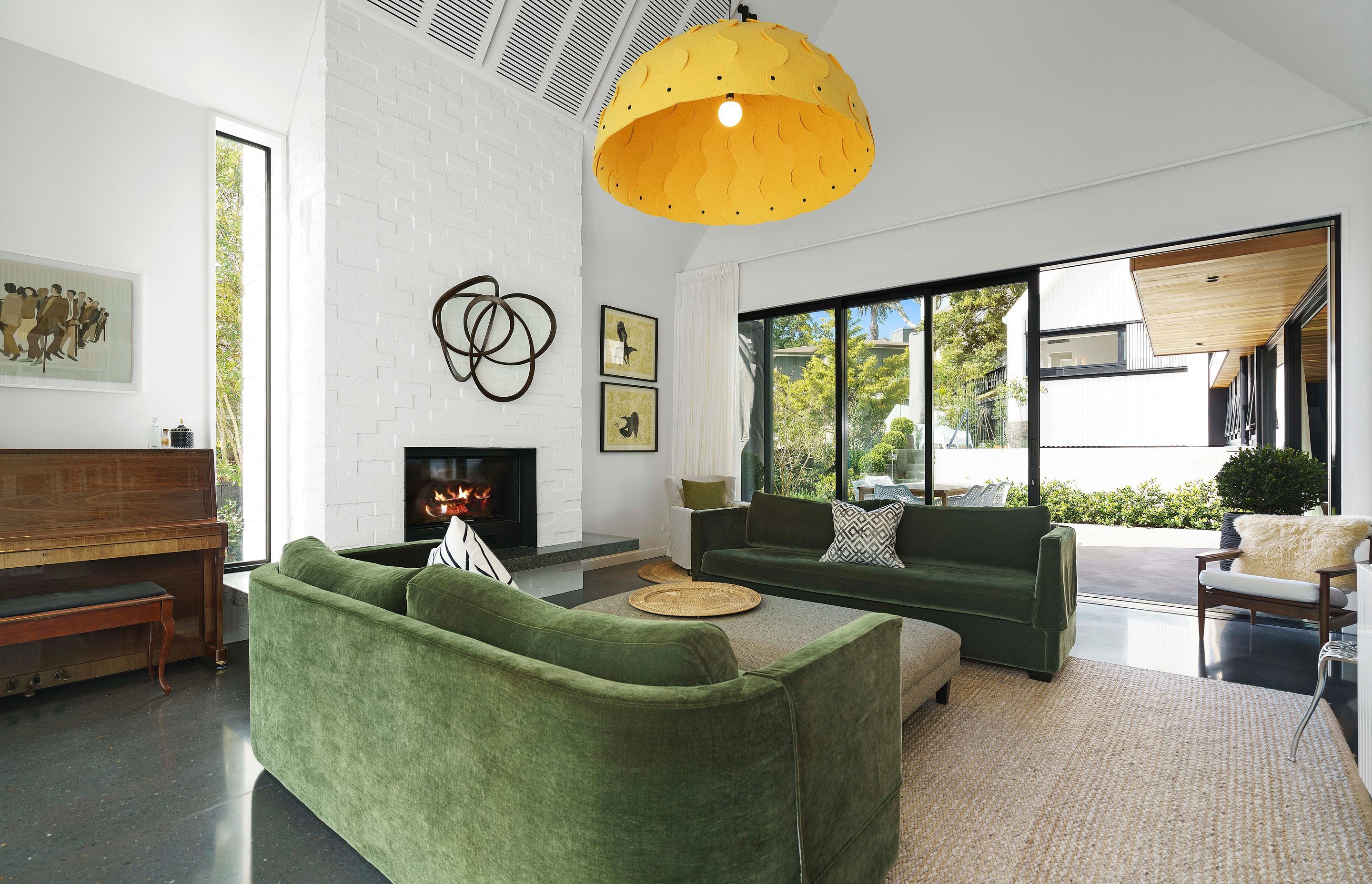 The skillion ceiling adds volumetric space to the living area while the bagged-brick chimney breast matches the exterior cladding of the white pavilions.