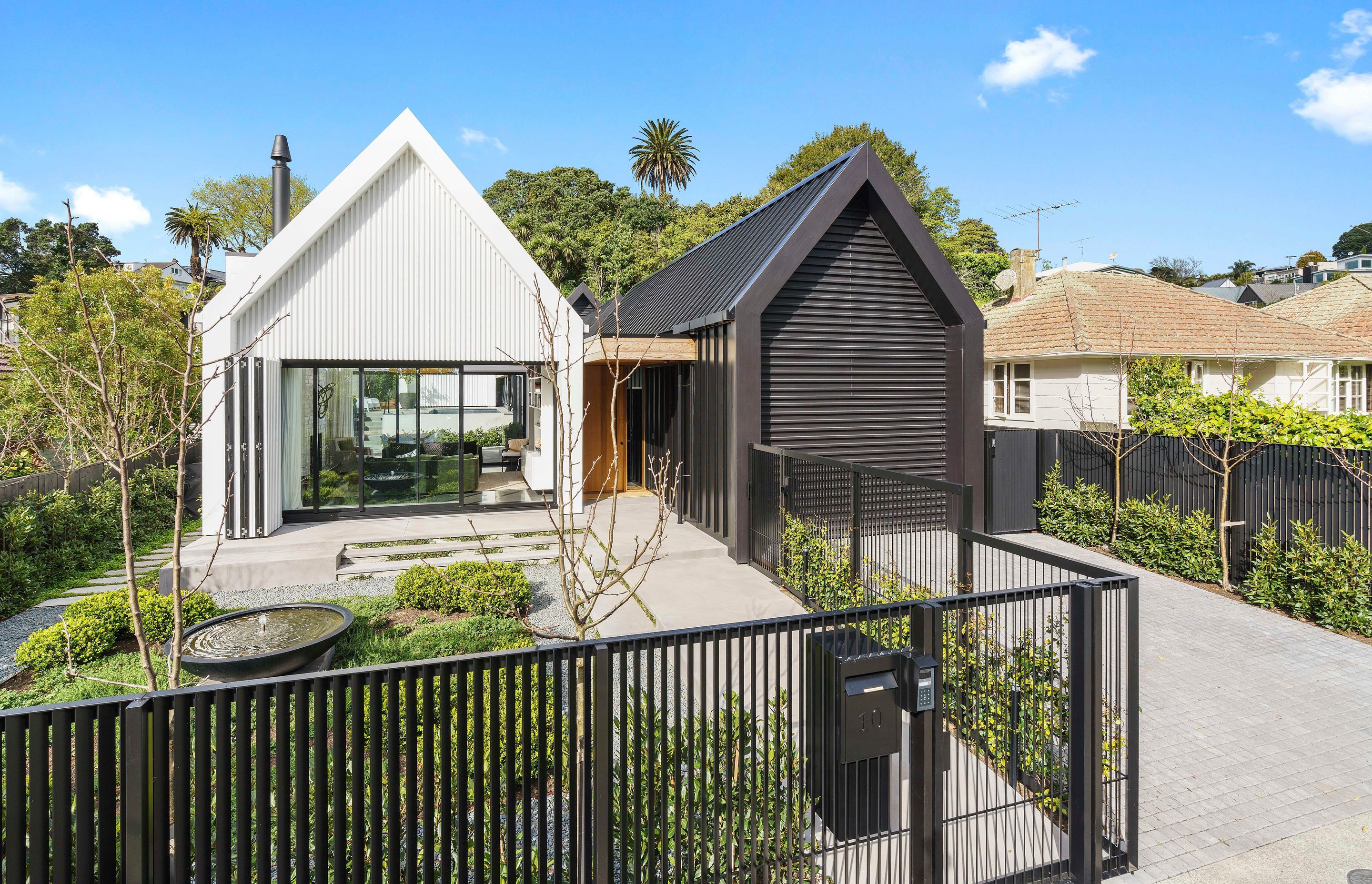 Reading as two striking pavilions from the road, this new home in the Auckland suburb of Remuera features various living zones that wrap around a large courtyard with tiled pool.