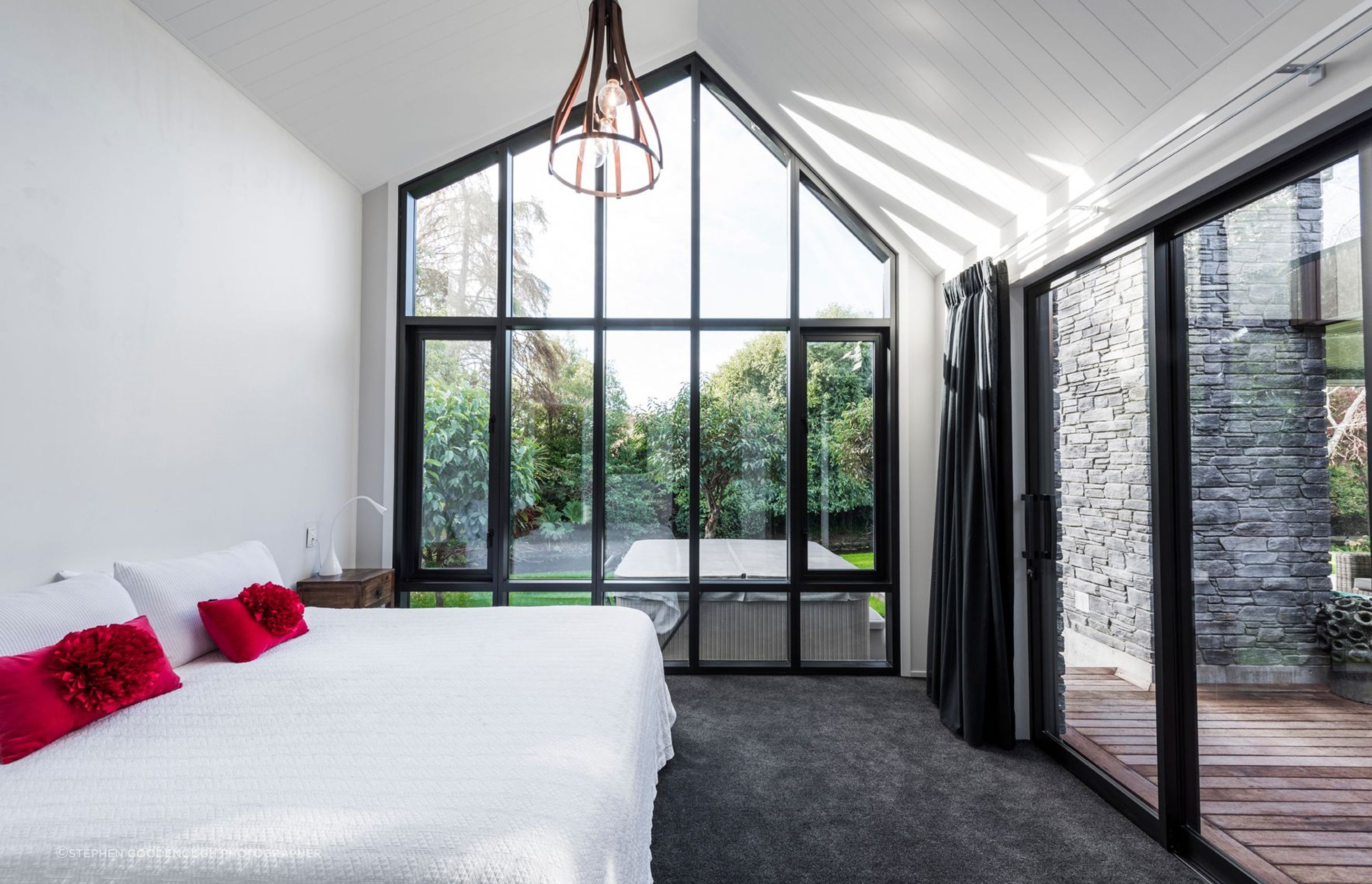 A bedroom with direct views out to the stream has the same asymmetrical apex repeated in its roofline.