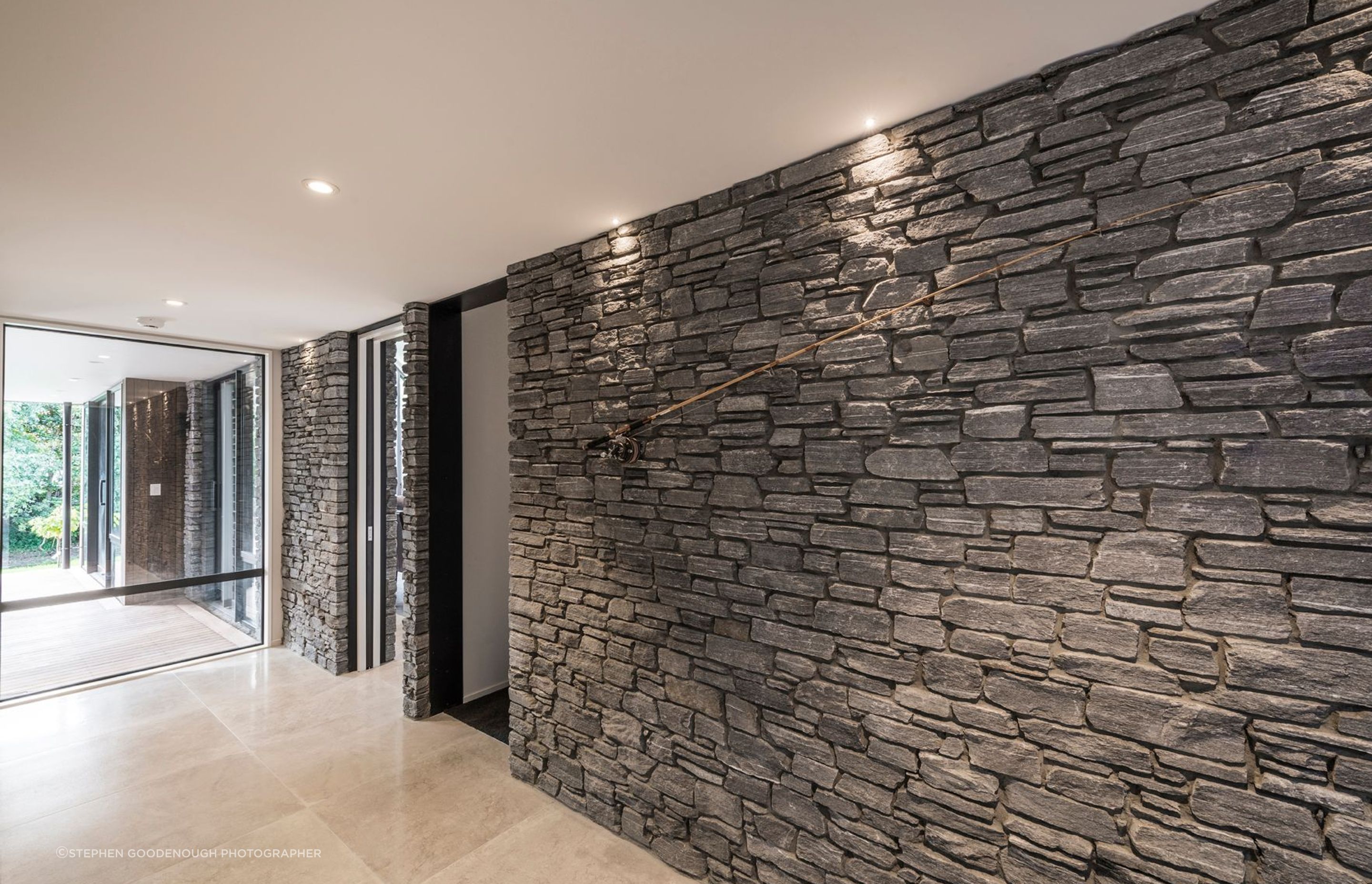 A wall of stone on one side of the entry hall, runs right through the home into the kitchen/dining space.