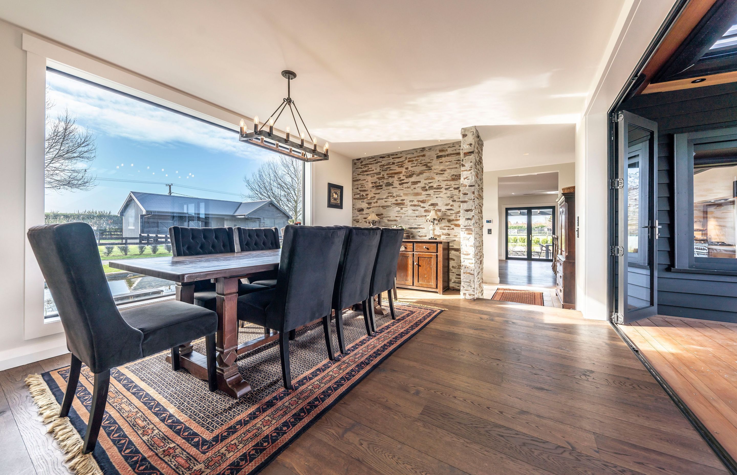 The formal dining area enjoys an elevated position with views over the pond through the large, plate glass window on one side and access to the external entertaining area on the other.
