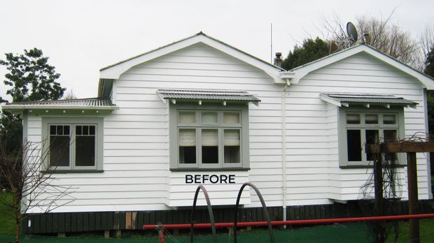 Front exterior view of a modest single-storey white weatherboard house, showing two gabled roof sections, decorative window hoods, sash-style windows, dark lower cladding, and a clearly visible “BEFORE” label. The image documents the pre-renovation condition of the facade.