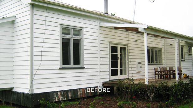 Exterior photograph of a single-storey weatherboard-clad house, labelled “BEFORE.” The facade has white horizontal siding, grey-trimmed windows, a glazed entry door, a shallow pitched corrugated roof, and a covered front veranda with timber posts and outdoor dining furniture. The building appears to be an older traditional residential property photographed prior to renovation.