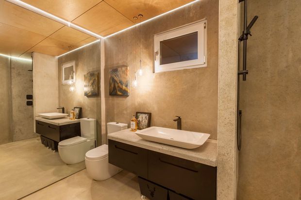 Warm contemporary bathroom featuring a wall-mounted dark timber vanity with a white vessel basin, separate toilet, large frameless mirror, walk-in shower with black fixtures, beige textured wall and floor finishes, a timber-look ceiling, and integrated LED strip lighting.