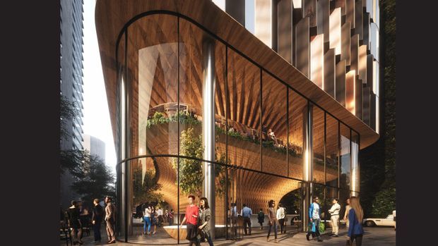 A high-quality architectural rendering of a tall urban commercial building entrance or lobby. The transparent double-height glazed facade reveals a dramatic timber-lined ceiling and walls, large arched black metal framing, integrated greenery, illuminated vertical columns, and multiple levels of interior activity. A tower facade rises behind the lobby, with pedestrians gathered along the street frontage.