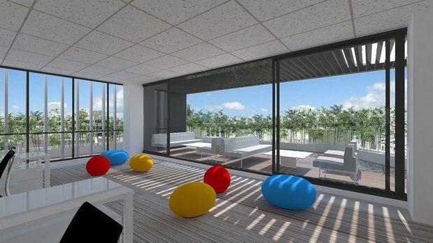 A bright contemporary office or commercial interior opening onto a large outdoor terrace. The space has full-height glazed doors and windows, a suspended acoustic tile ceiling, white built-in cabinetry or work surfaces, and several colorful rounded lounge seats. Strong linear shadows from the external louvres fall across the floor, with outdoor seating visible beyond the glazing.