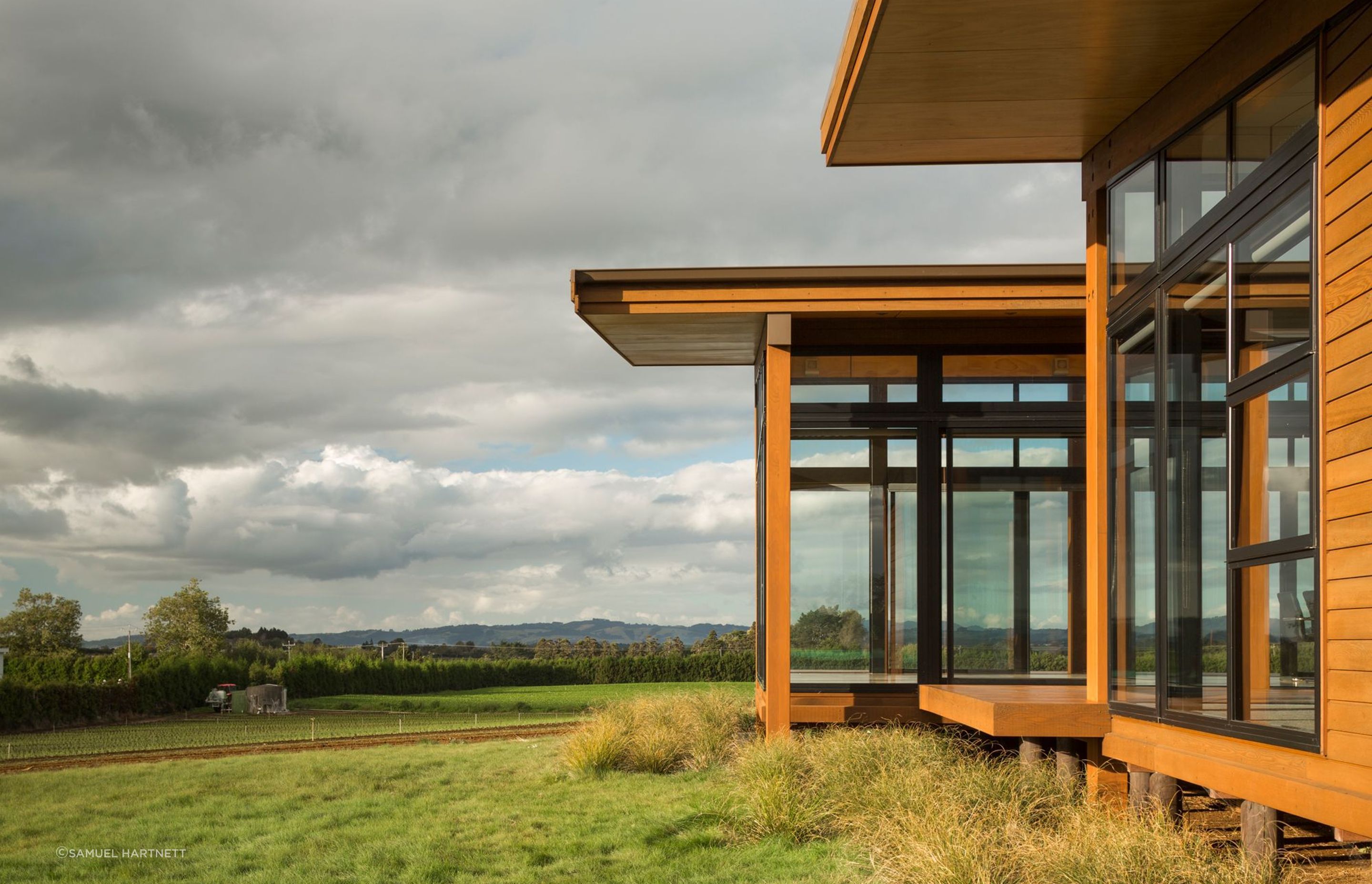 Generous timber overhangs reflect the cedar weatherboards stain used to clad the modern farming home.