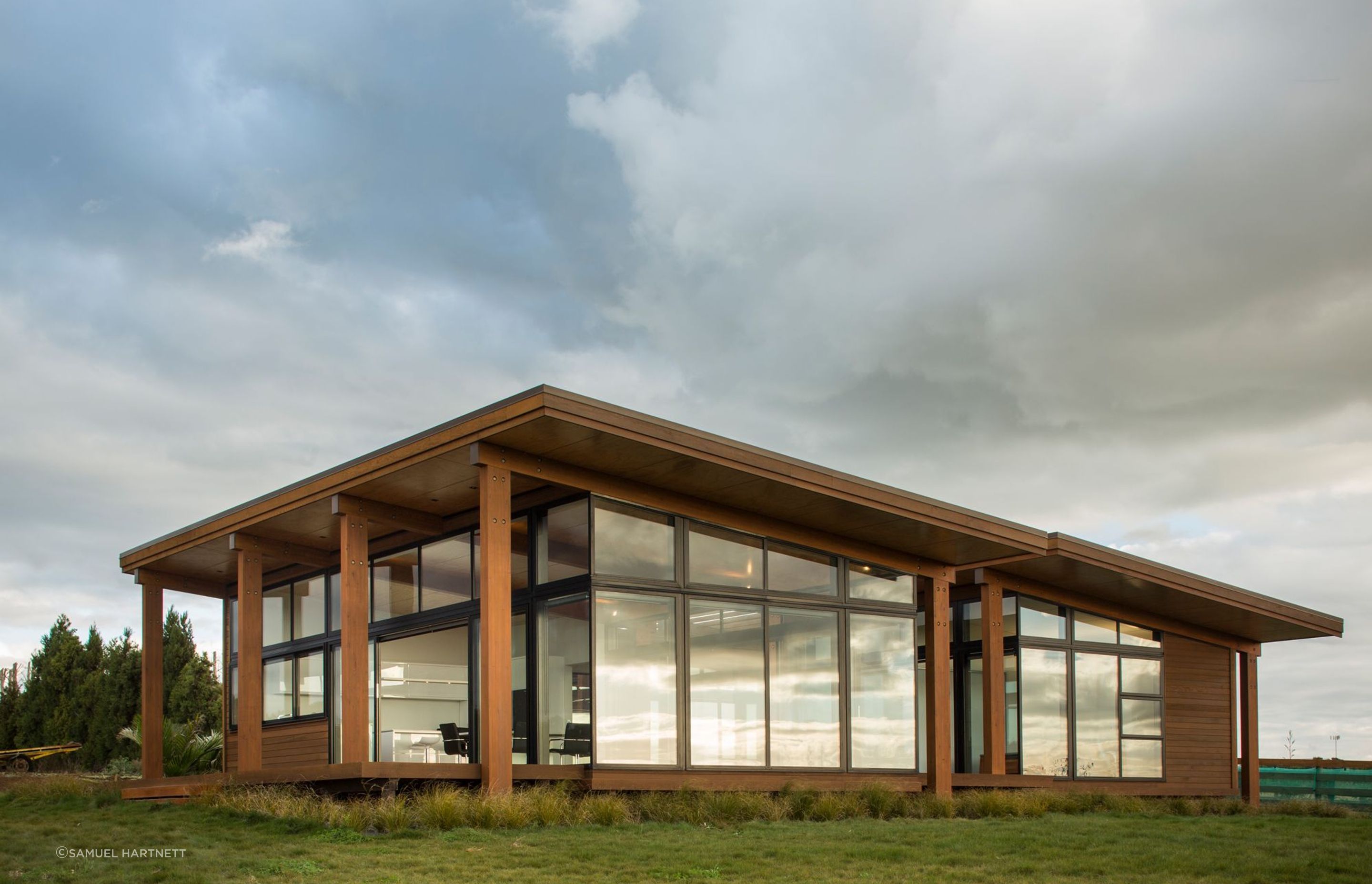 Macrocarpa rain screen and Cedar weatherboards are broken up with expansive full height glazing overlooking the surrounding landscape.