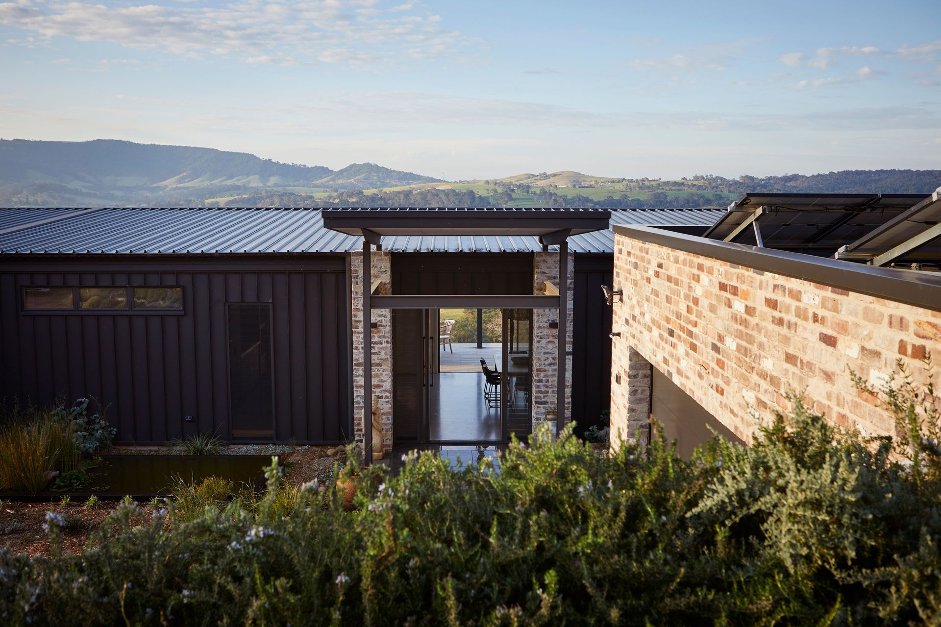 Solidified in black cladding and recycled brick to reflect the home’s surrounding grounds and uninterrupted views.