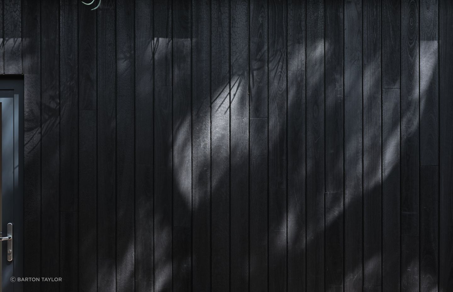 Recycled Shou Sugi Ban cladding fosters a harmonious cohesion with the surrounding environment.