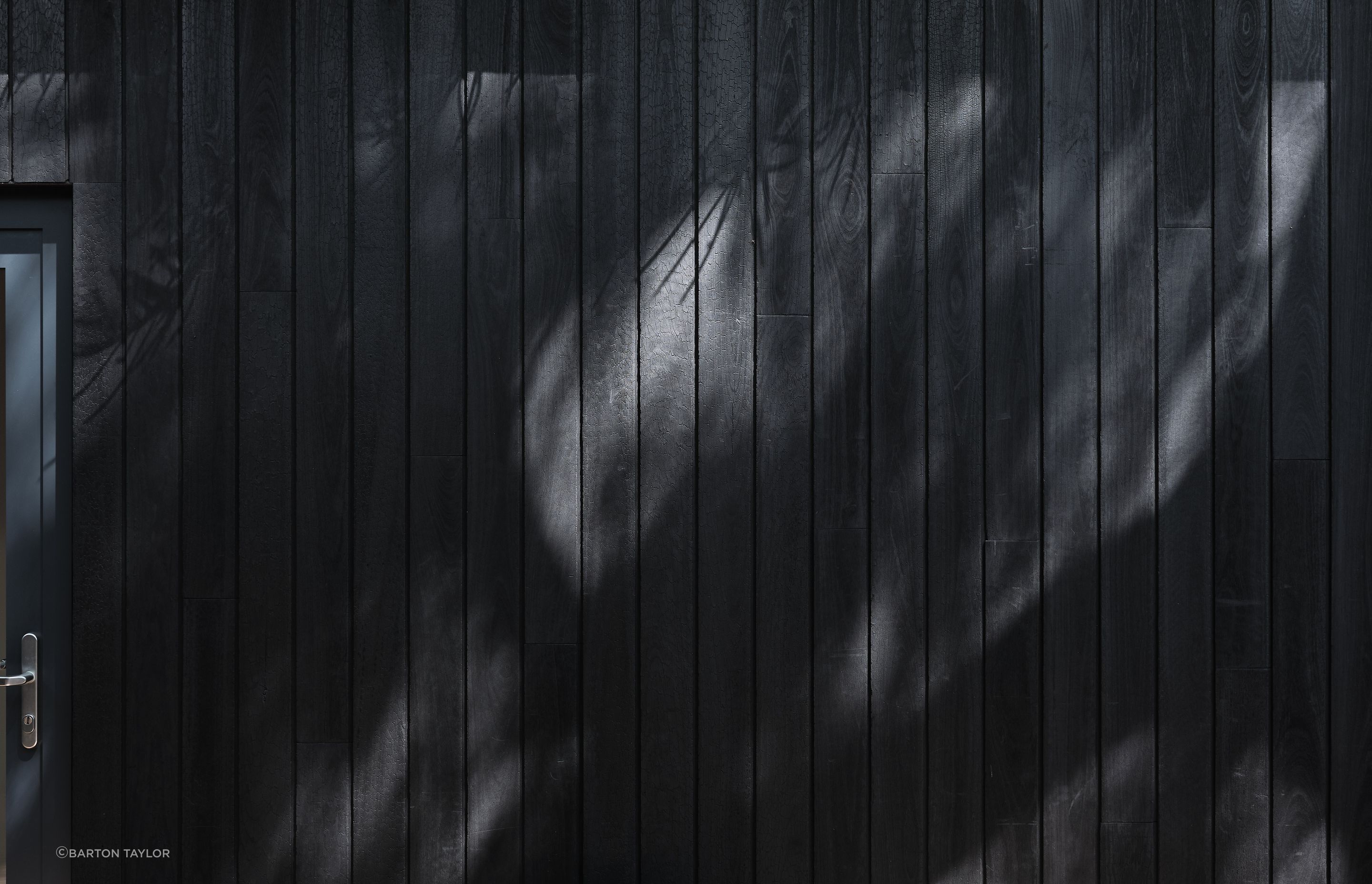 Recycled Shou Sugi Ban cladding fosters a harmonious cohesion with the surrounding environment.