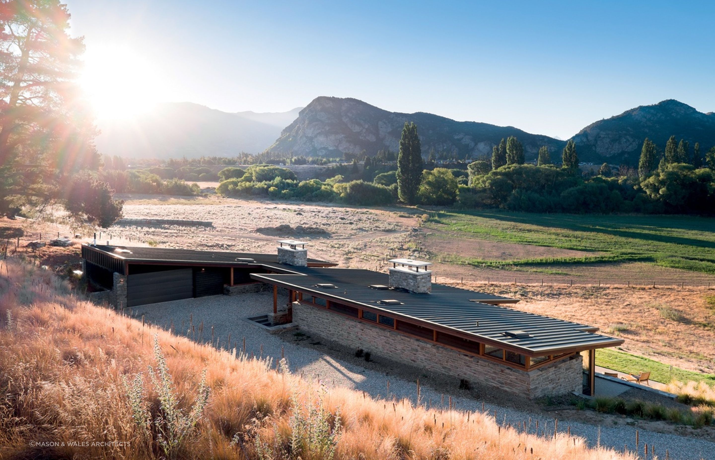 The distinctive sharp, sloping roof and two large schist chimneys of the Cardrona River House by Mason &amp; Wales Architects are great features of this impressive home. | Photography: Dennis Radermacher