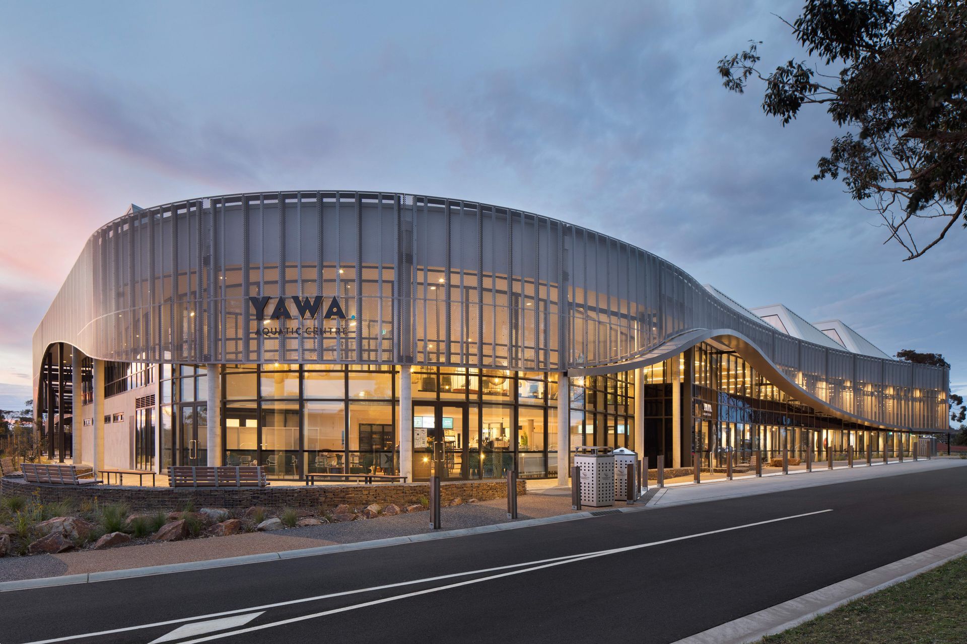 Appearing single-level from the street, the perforated steel screen wraps around the centre masking a first-level gymnasium.