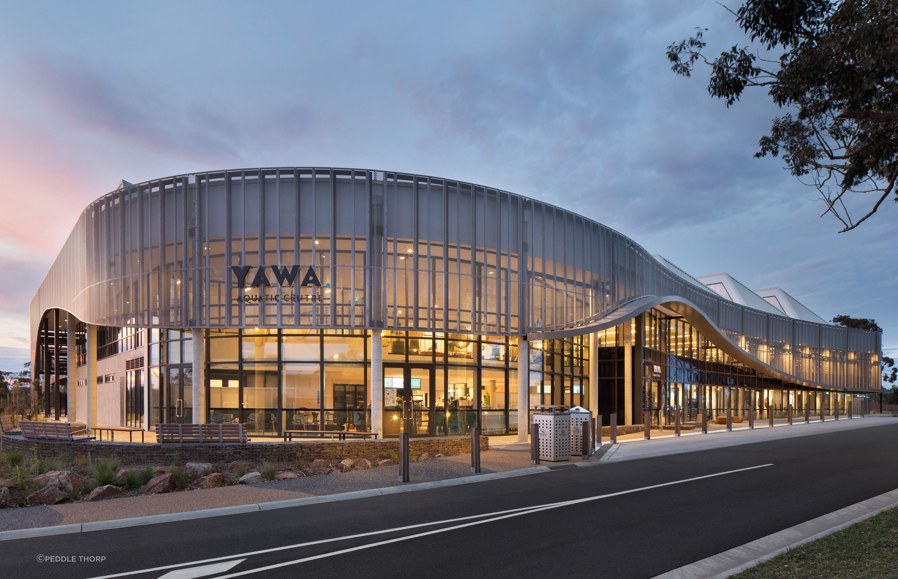 Appearing single-level from the street, the perforated steel screen wraps around the centre masking a first-level gymnasium.