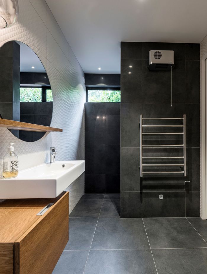 This bathroom features a porcelein vanity that is offset from the timber cabinetry; and floor to ceiling tiles.