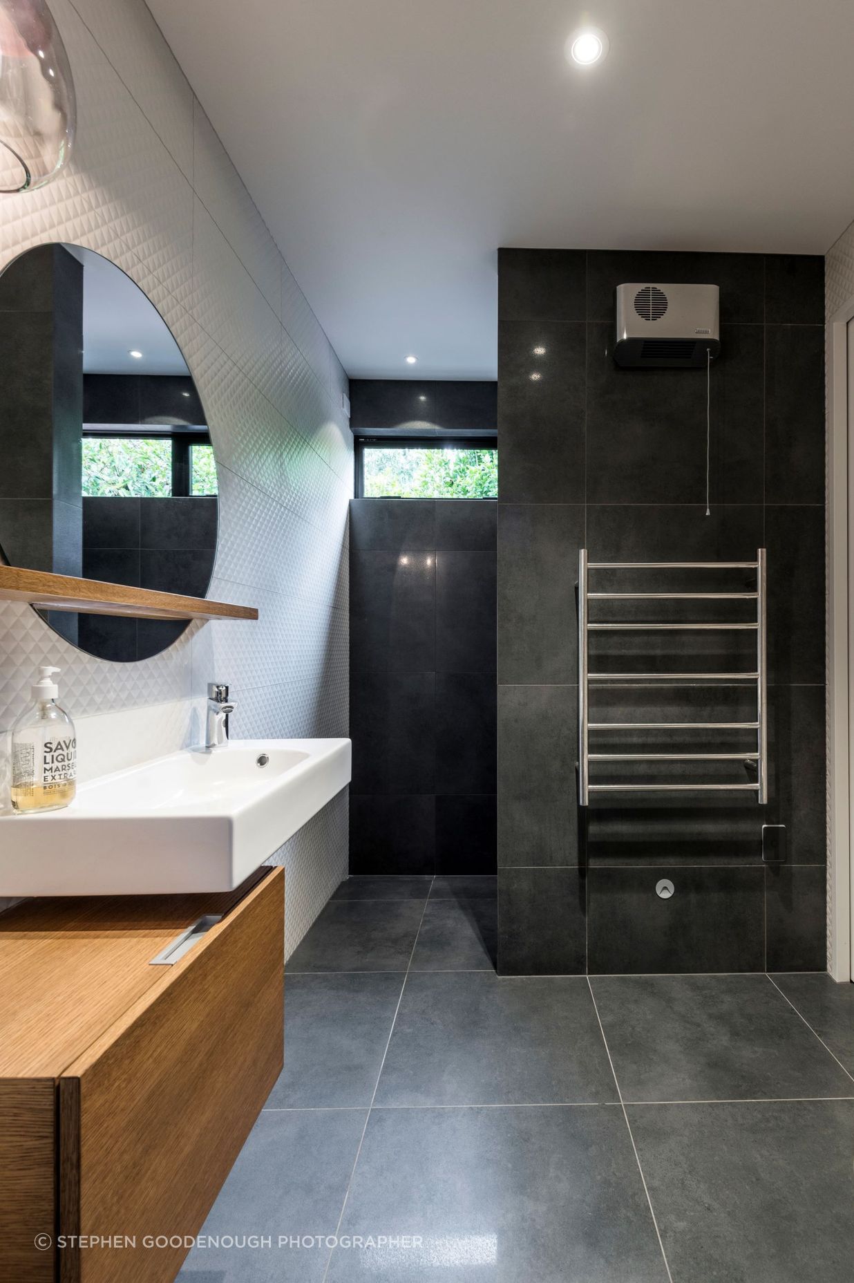 This bathroom features a porcelein vanity that is offset from the timber cabinetry; and floor to ceiling tiles.