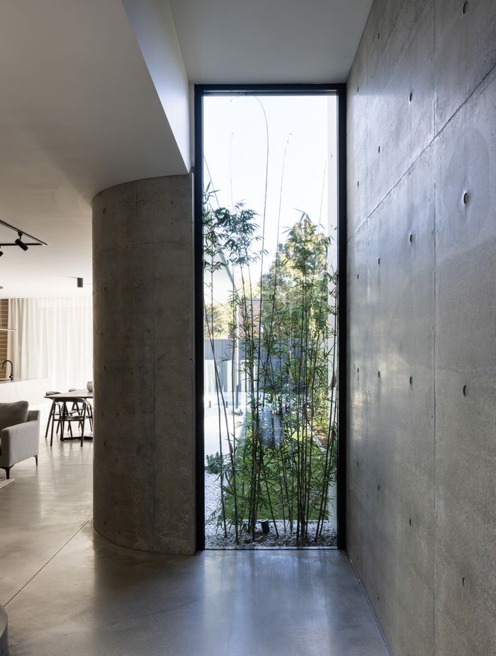 A floor to ceiling window displaying greenery lightens the polished concrete.