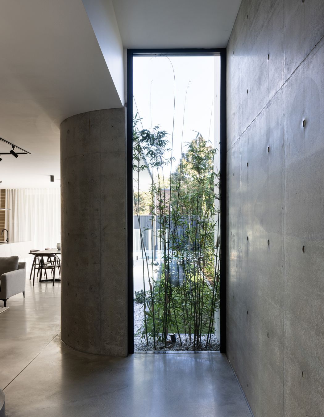 A floor to ceiling window displaying greenery lightens the polished concrete.