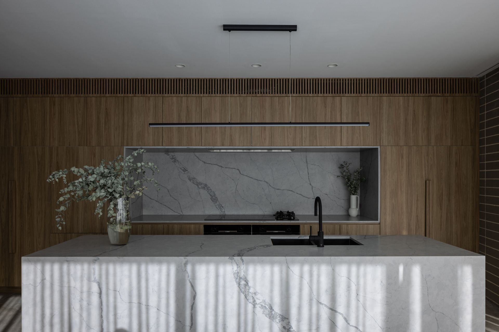 Solid materiality softened with warm timber tones.